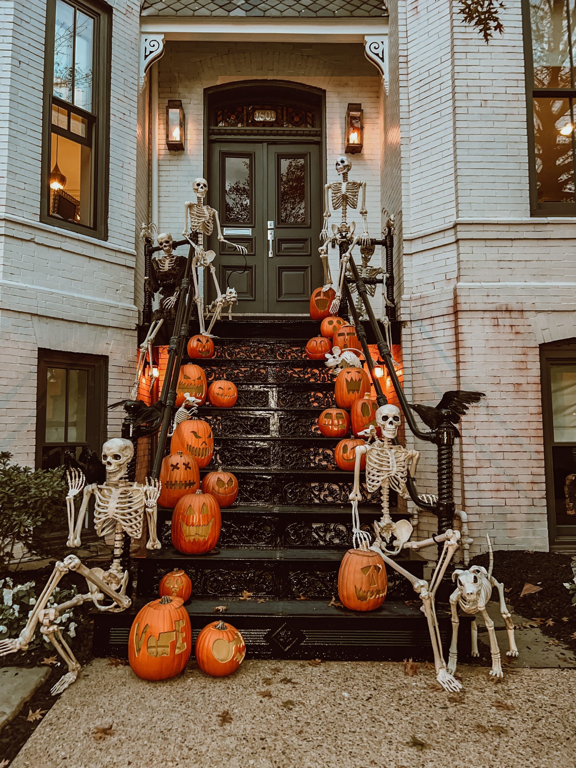 Creepy Halloween scene with skeletons and carved pumpkins decorating outdoor stairs.