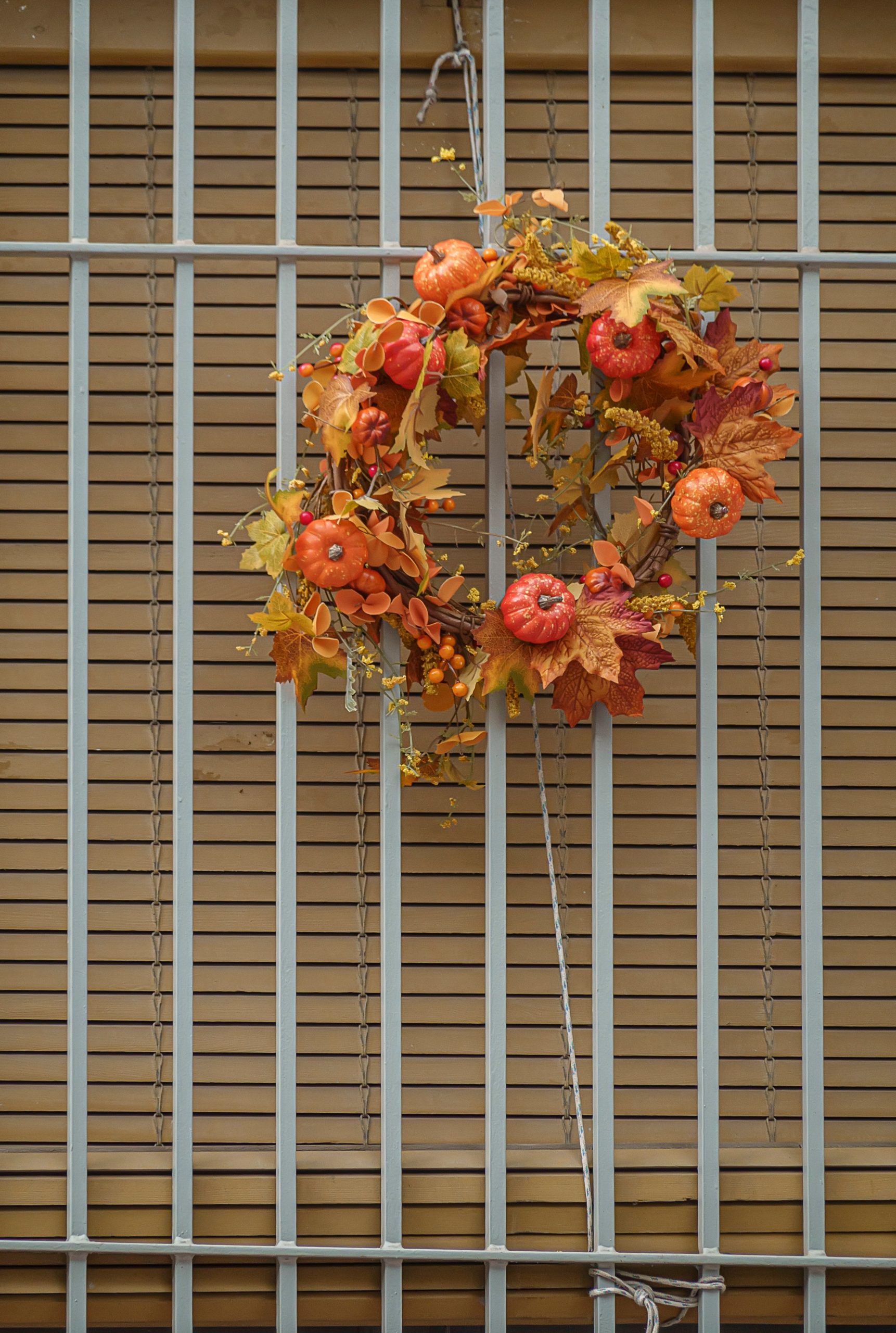 Decorative autumn wreath with mini pumpkins on a metal grate in San Vicente, Spain.