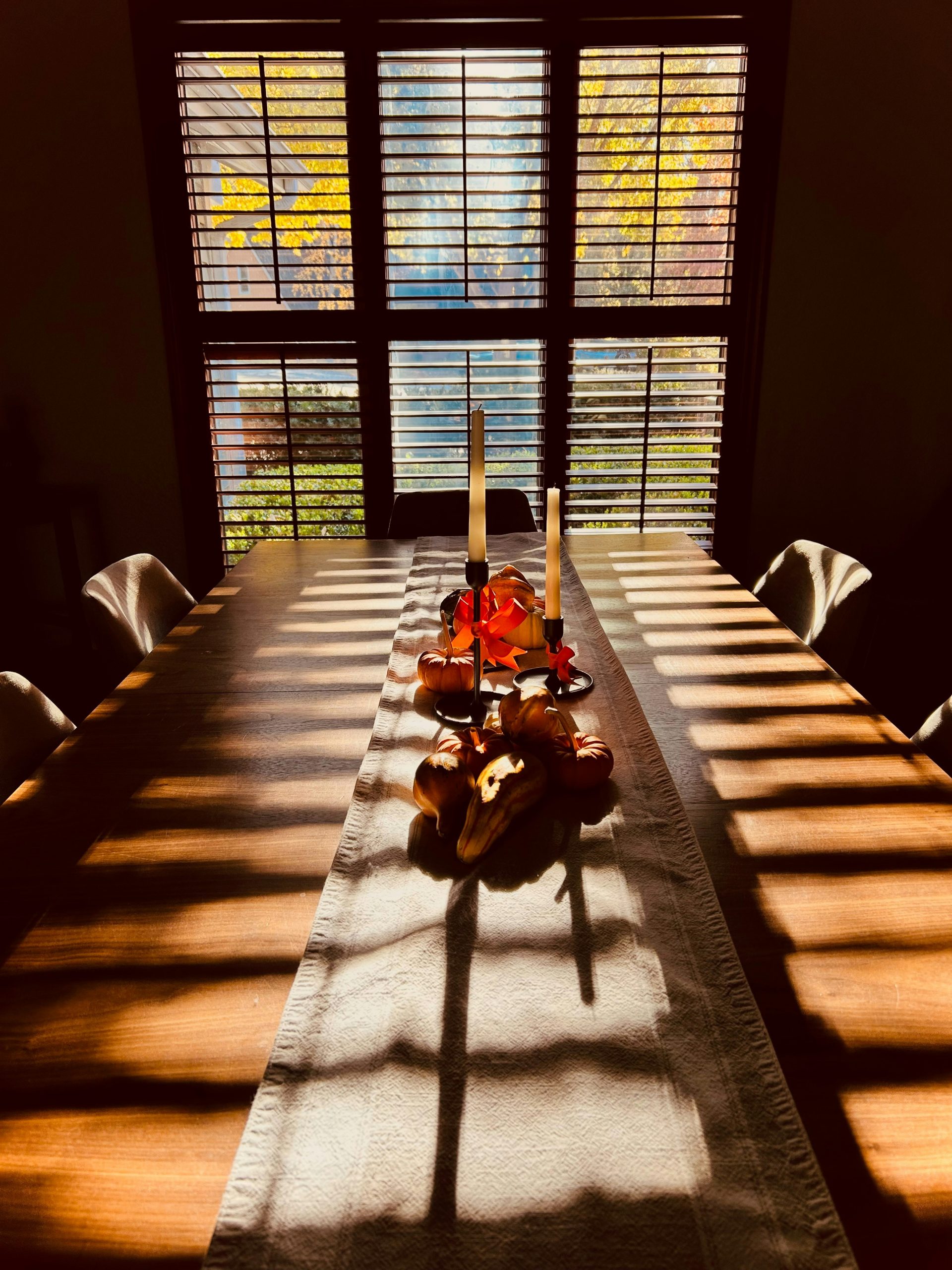 Dining table with autumn foliage visible through window