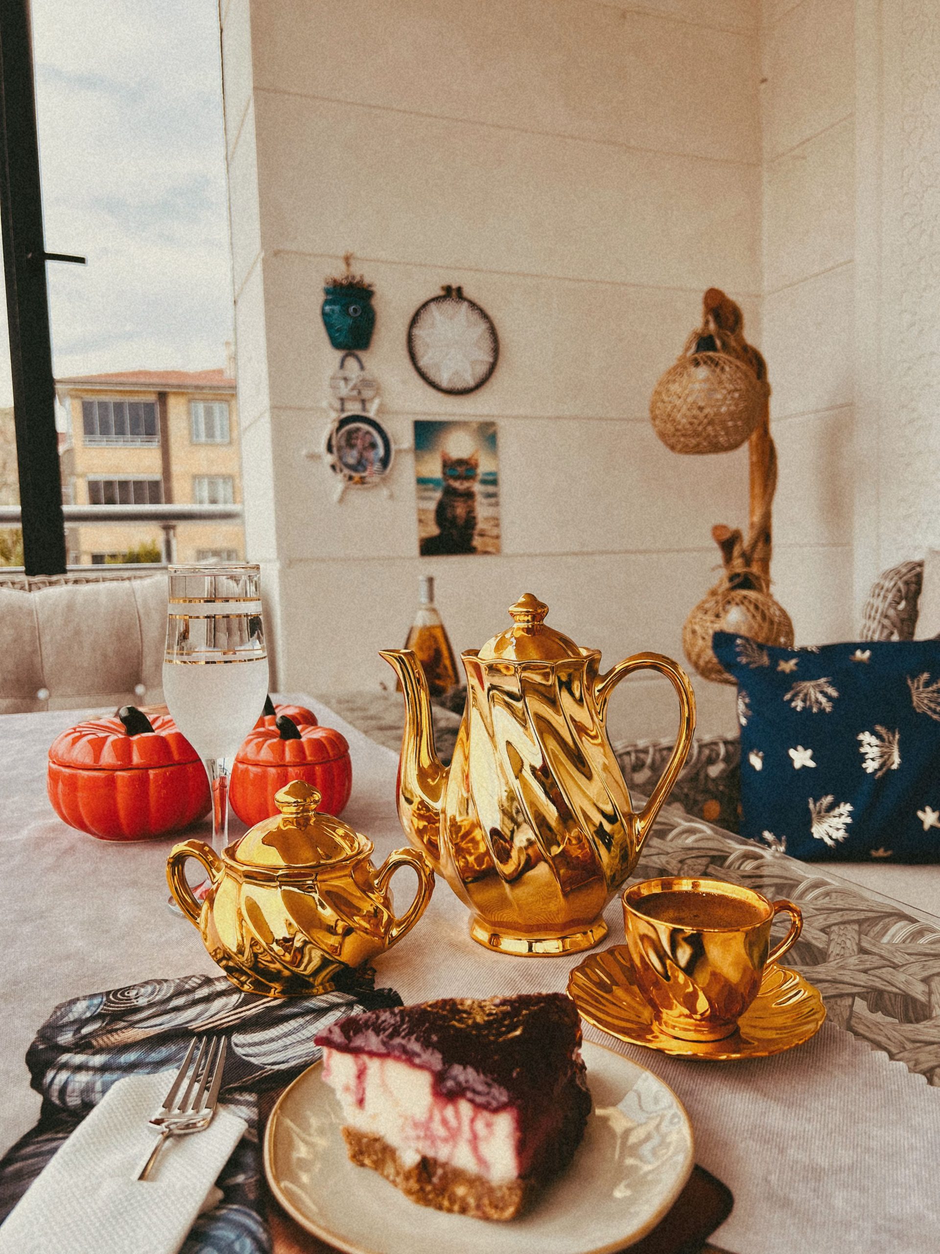 Elegant afternoon tea with gold teapot and berry cheesecake in cozy setting.