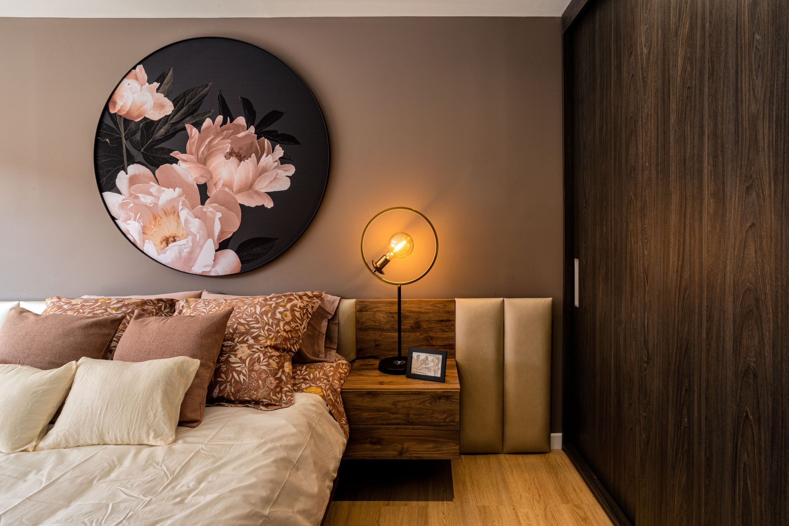 Elegant bedroom interior featuring floral artwork and warm lighting creating a cozy atmosphere.