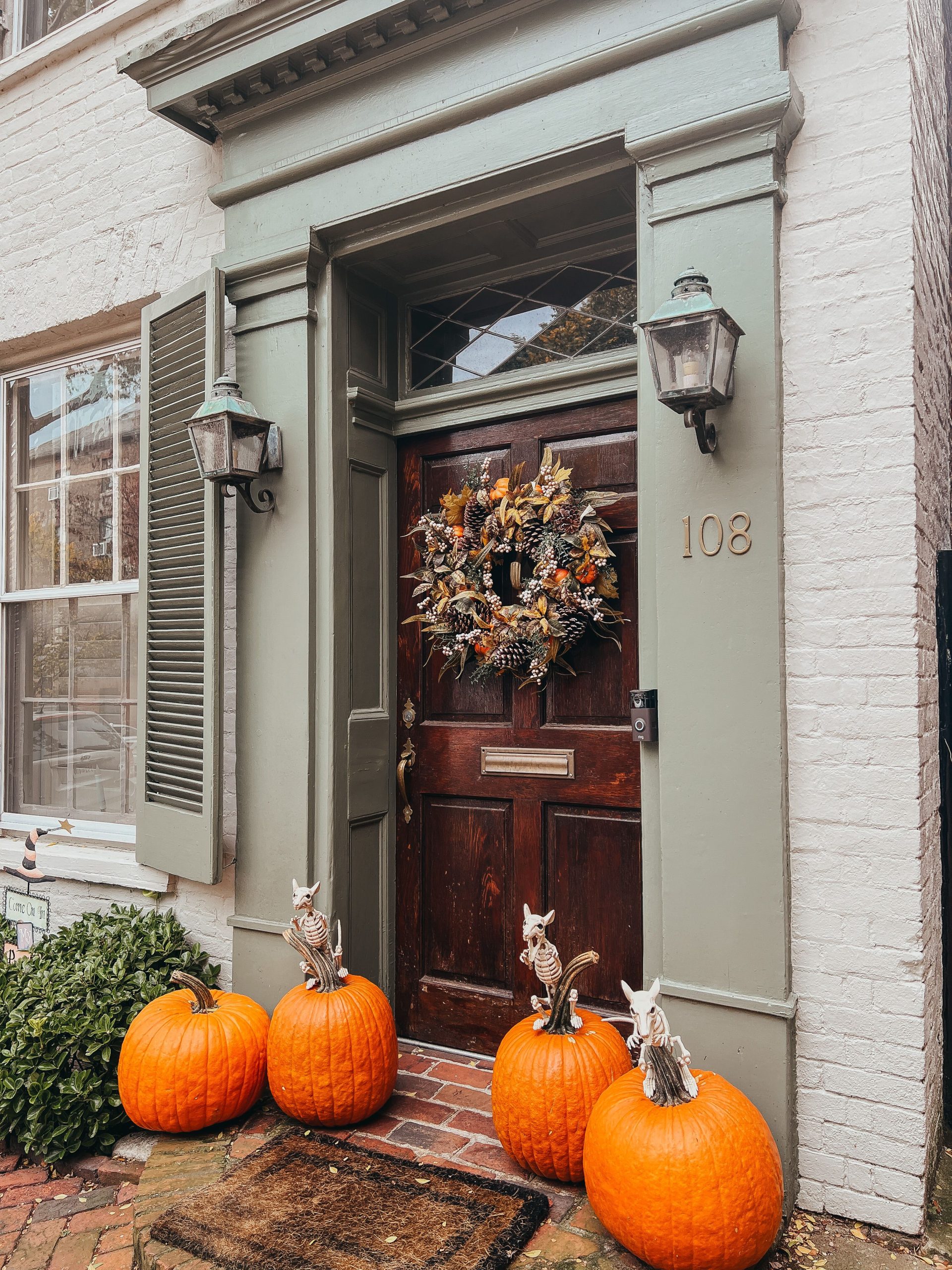 Elegant doorway adorned with pumpkins and autumn wreath, showcasing festive Halloween decor.