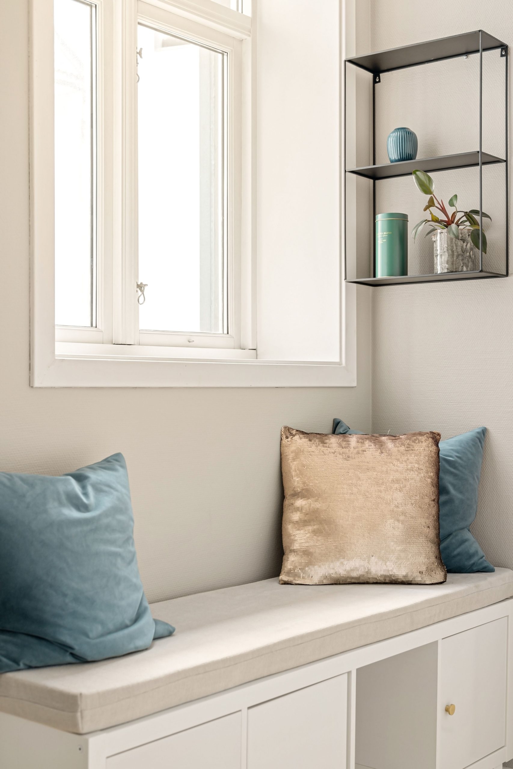 Elegant indoor nook with plush pillows, modern shelving, and soft natural light.