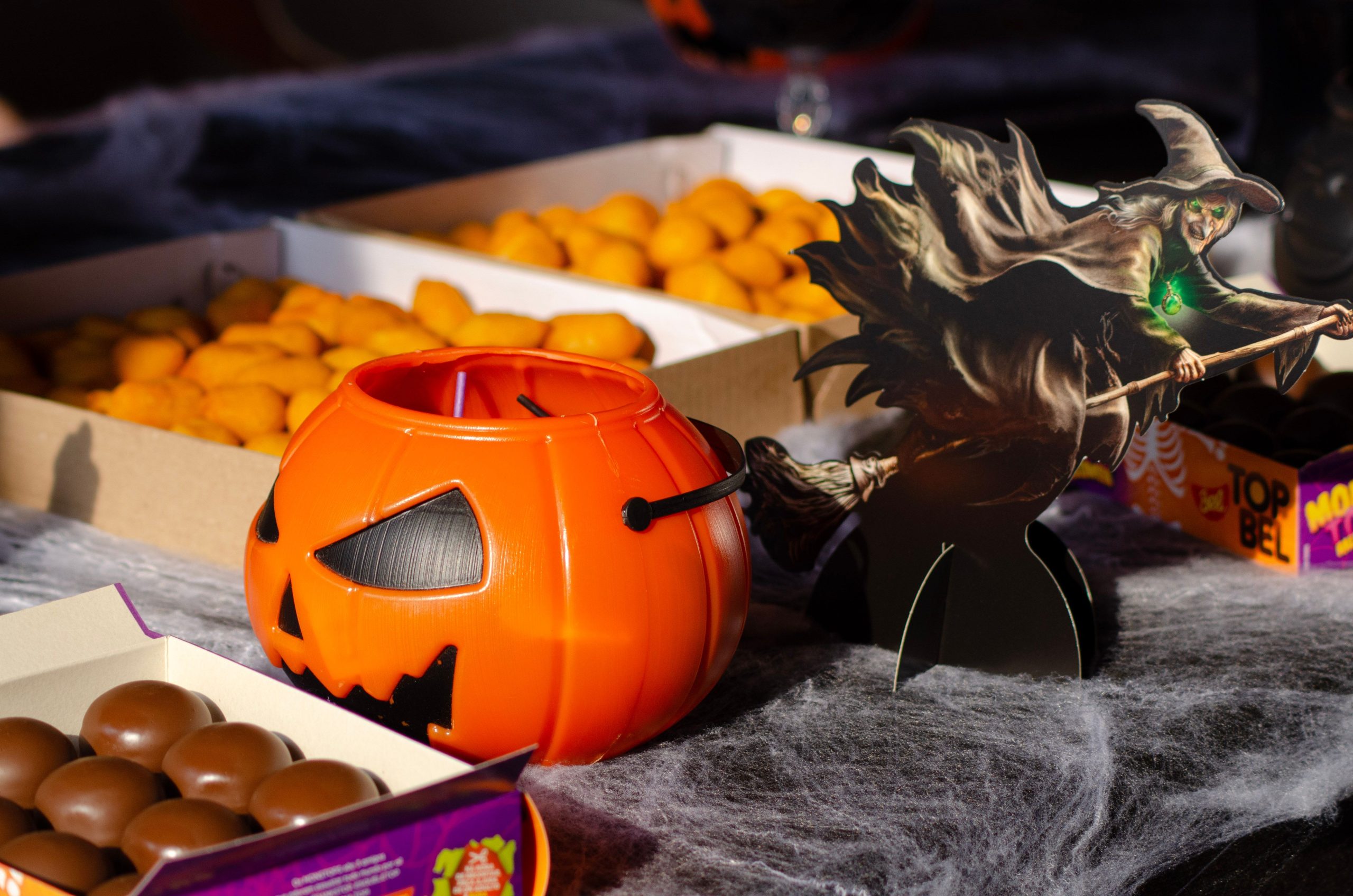 Festive Halloween candy arrangement with a pumpkin bucket and witch cutout.