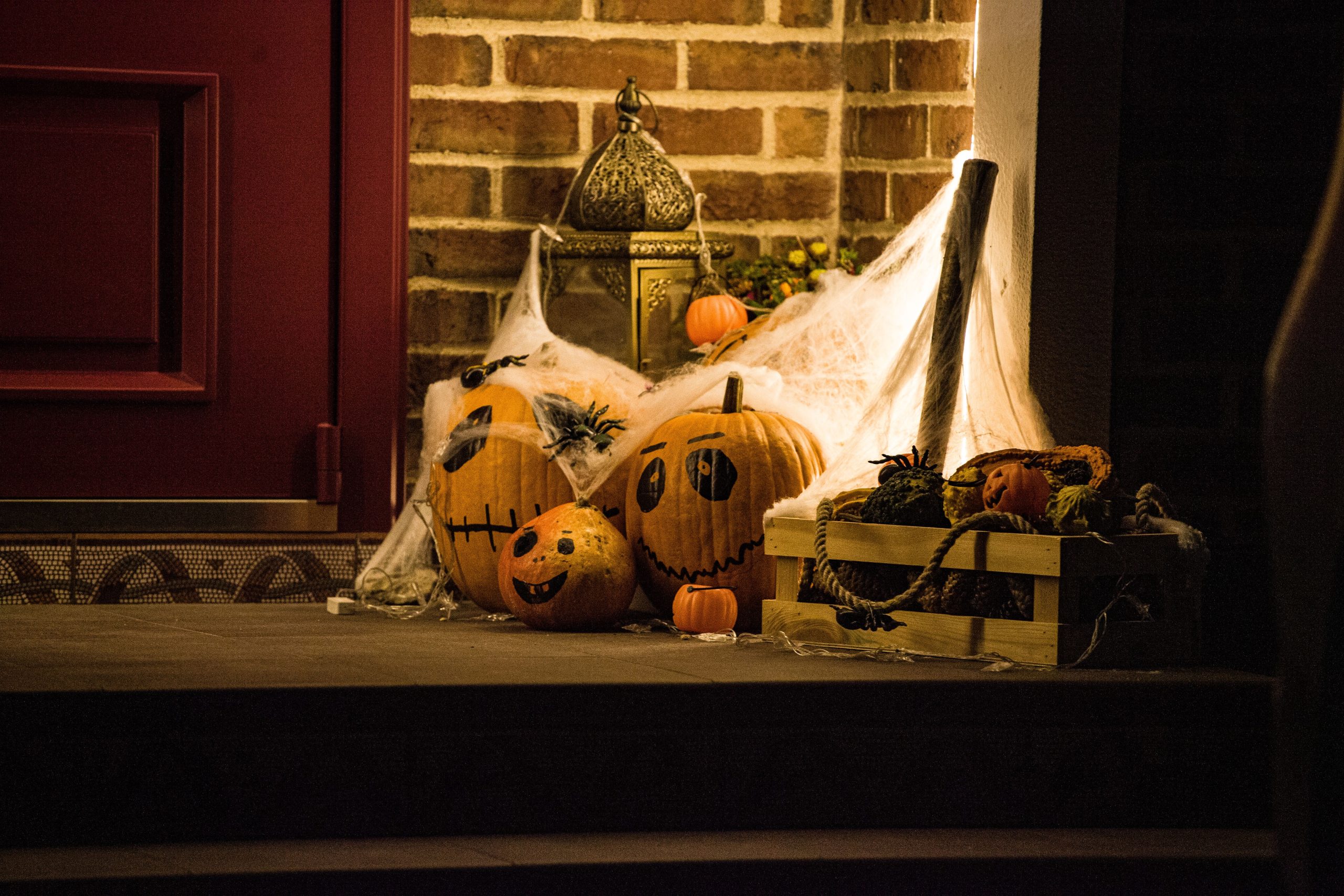 Festive Halloween decor featuring carved pumpkins and cobwebs at a doorstep.