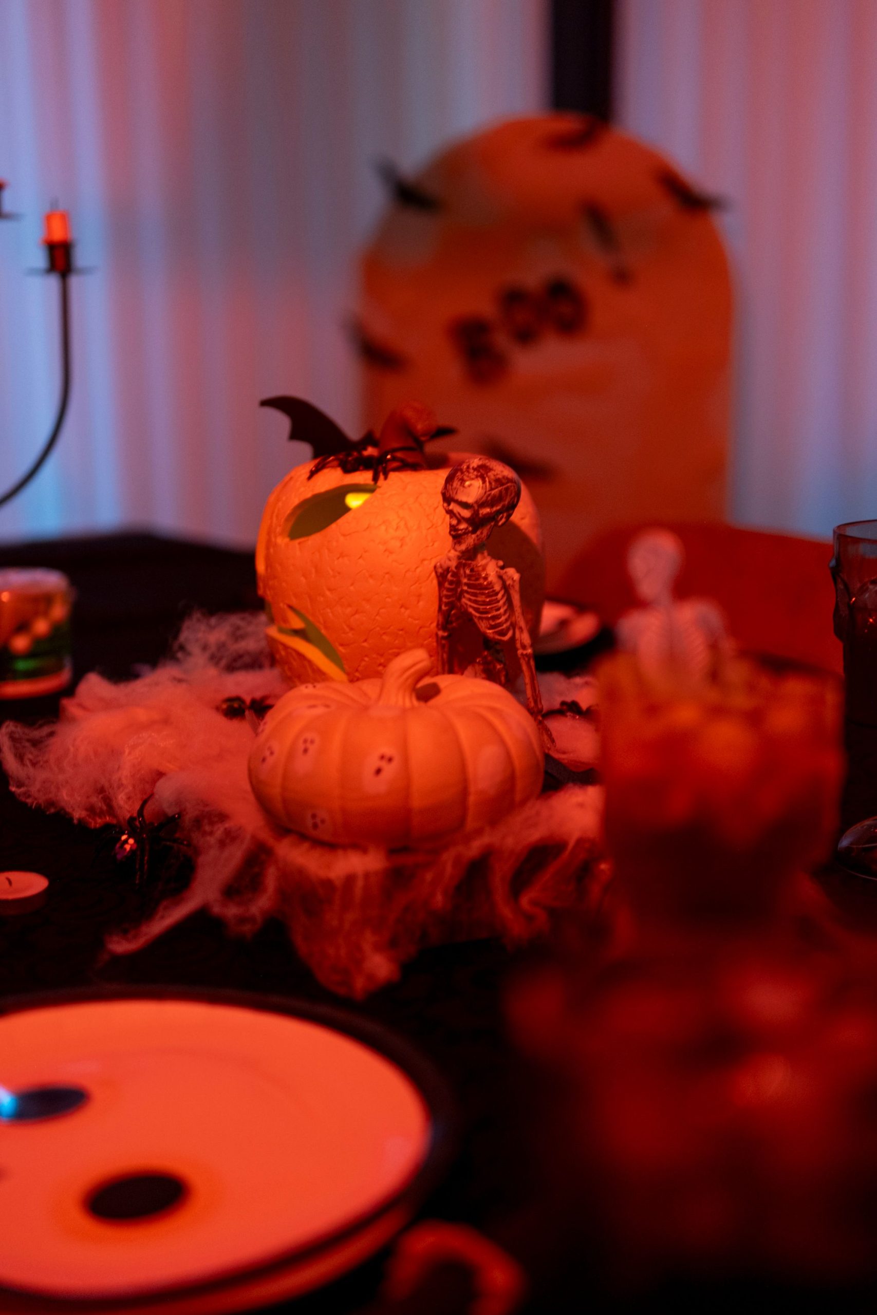 Halloween-themed table with carved pumpkins, skeleton, and spider web decor set for a spooky celebration.