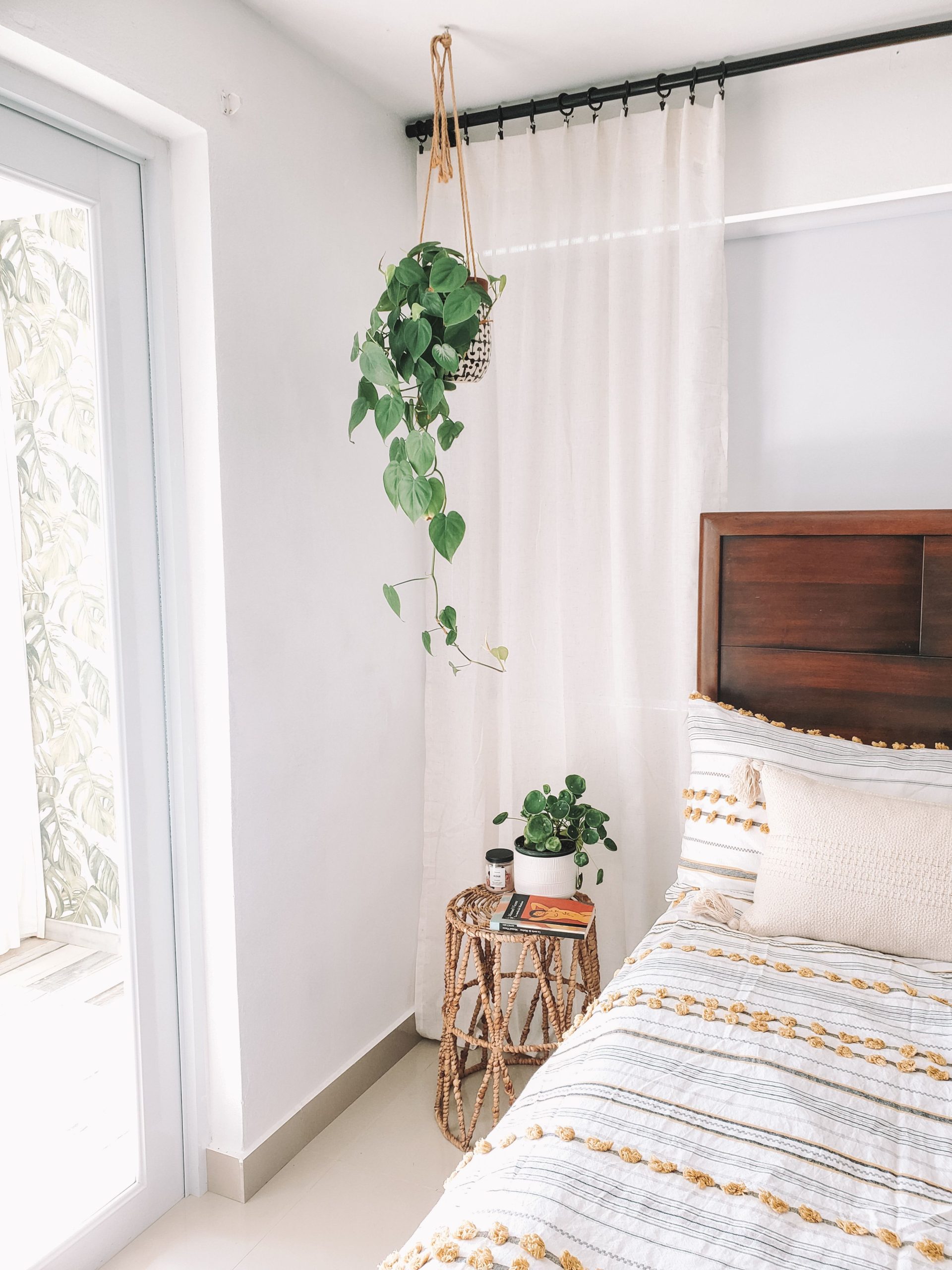 Minimalist bohemian bedroom with cozy decor and lush indoor plants.