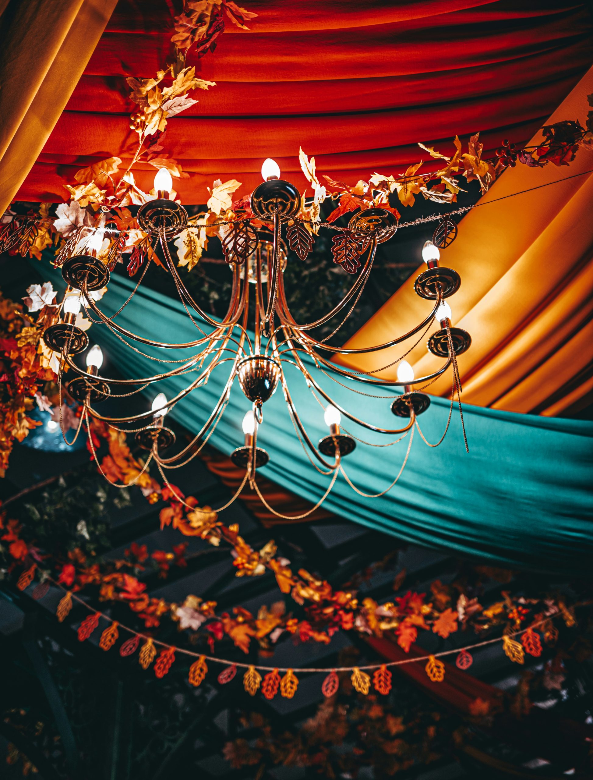 Ornate chandelier hangs amidst autumn leaf decorations