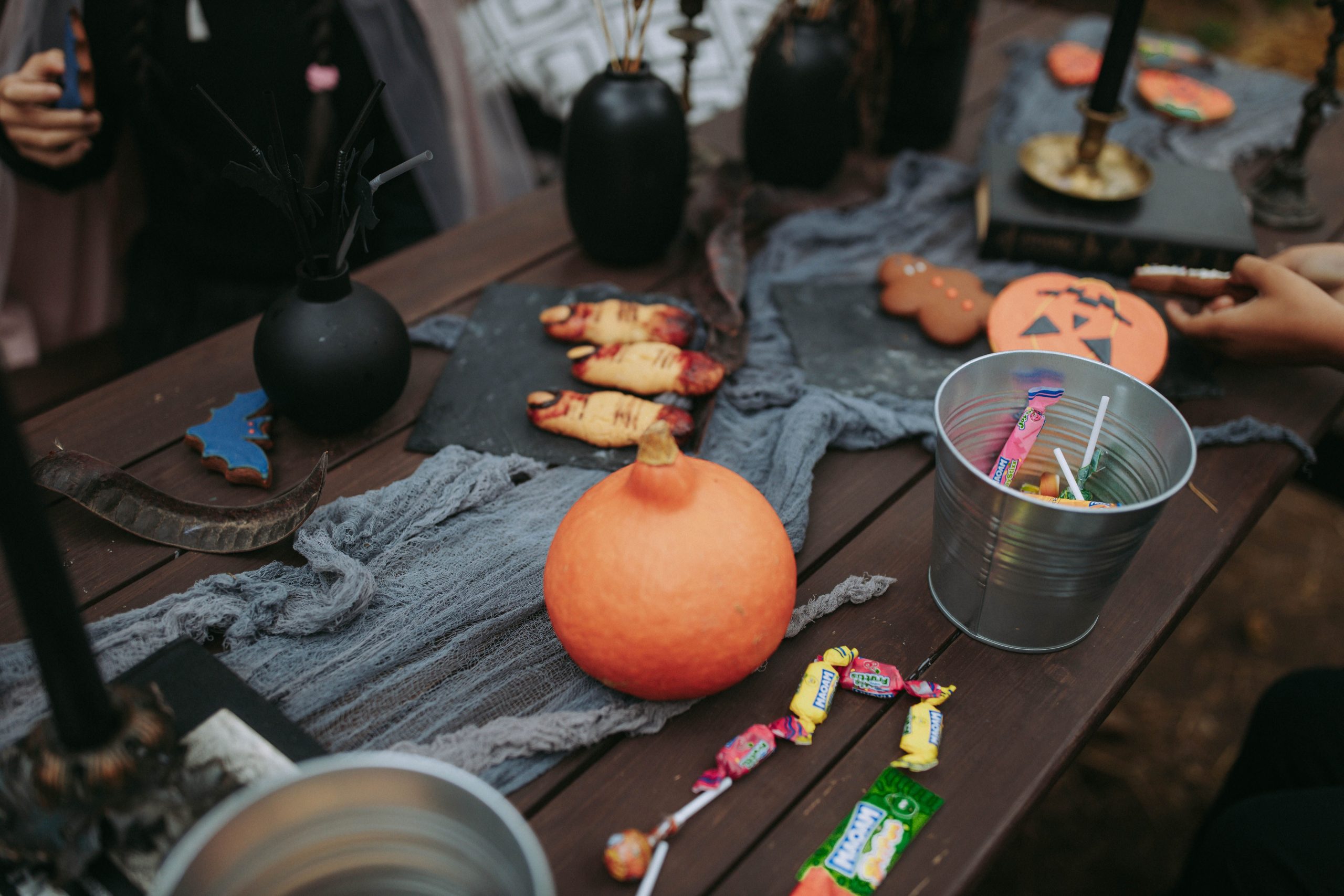 Rustic Halloween table with treats, pumpkin, candies, and spooky decorations.
