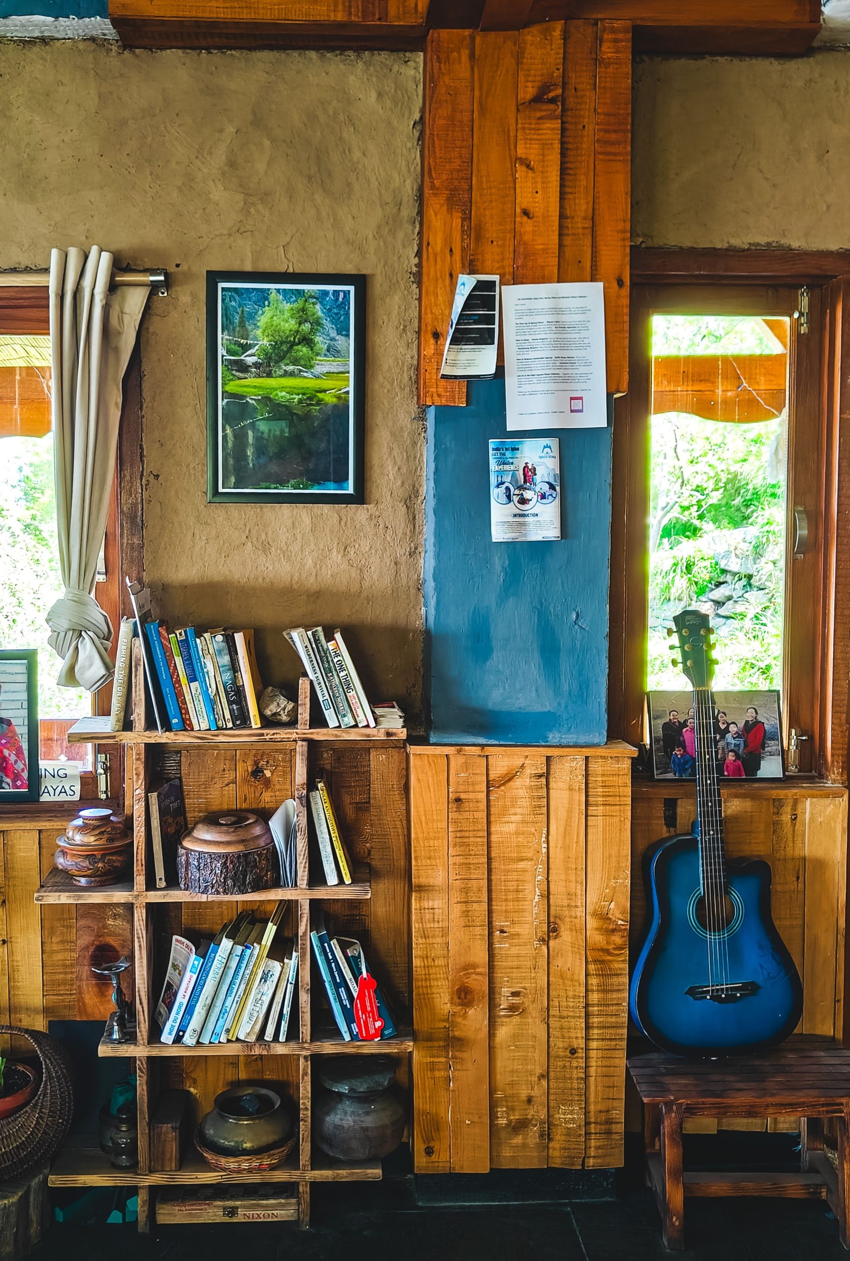 Rustic interior featuring a bookshelf, blue guitar, and framed artwork, embodying a cozy and eclectic vibe.