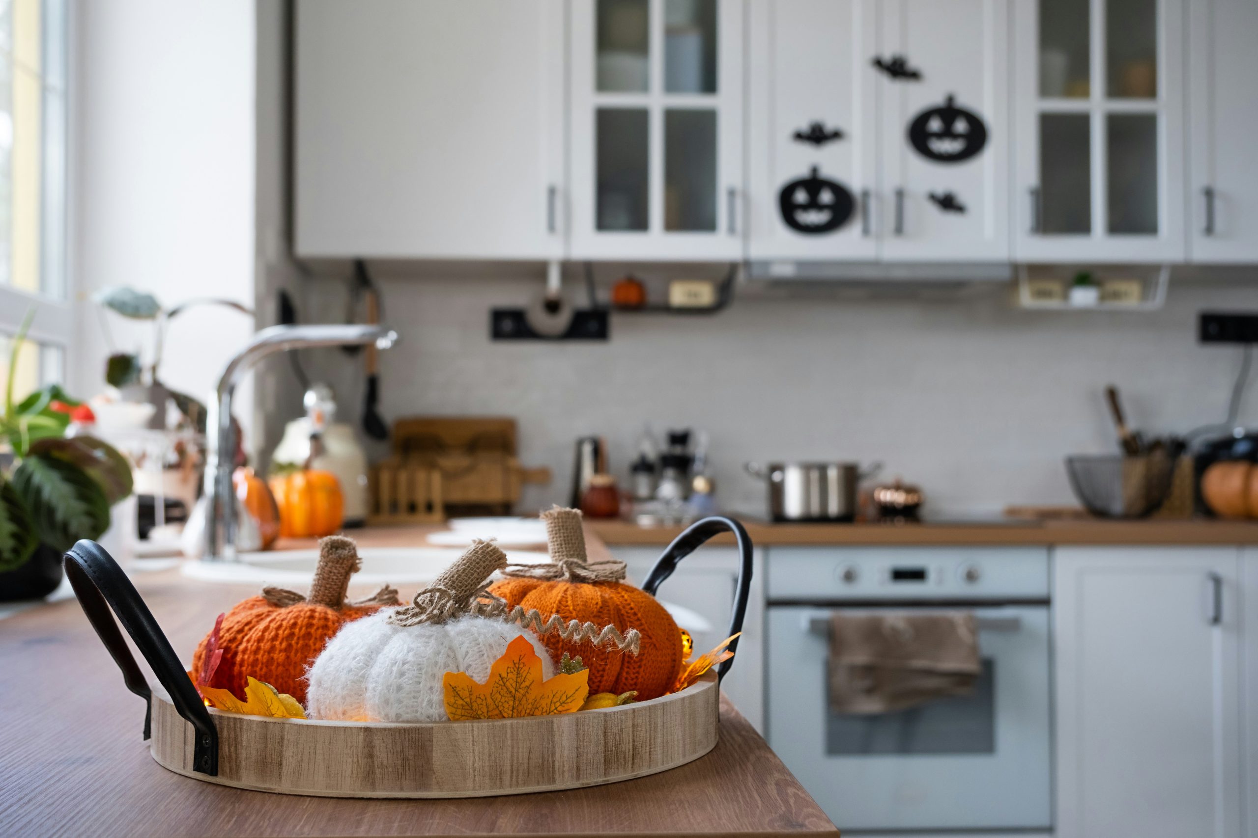 The interior of the Scandi-style white kitchen is decorated with pumpkins for Halloween. Autumn mood, home decor for the holiday