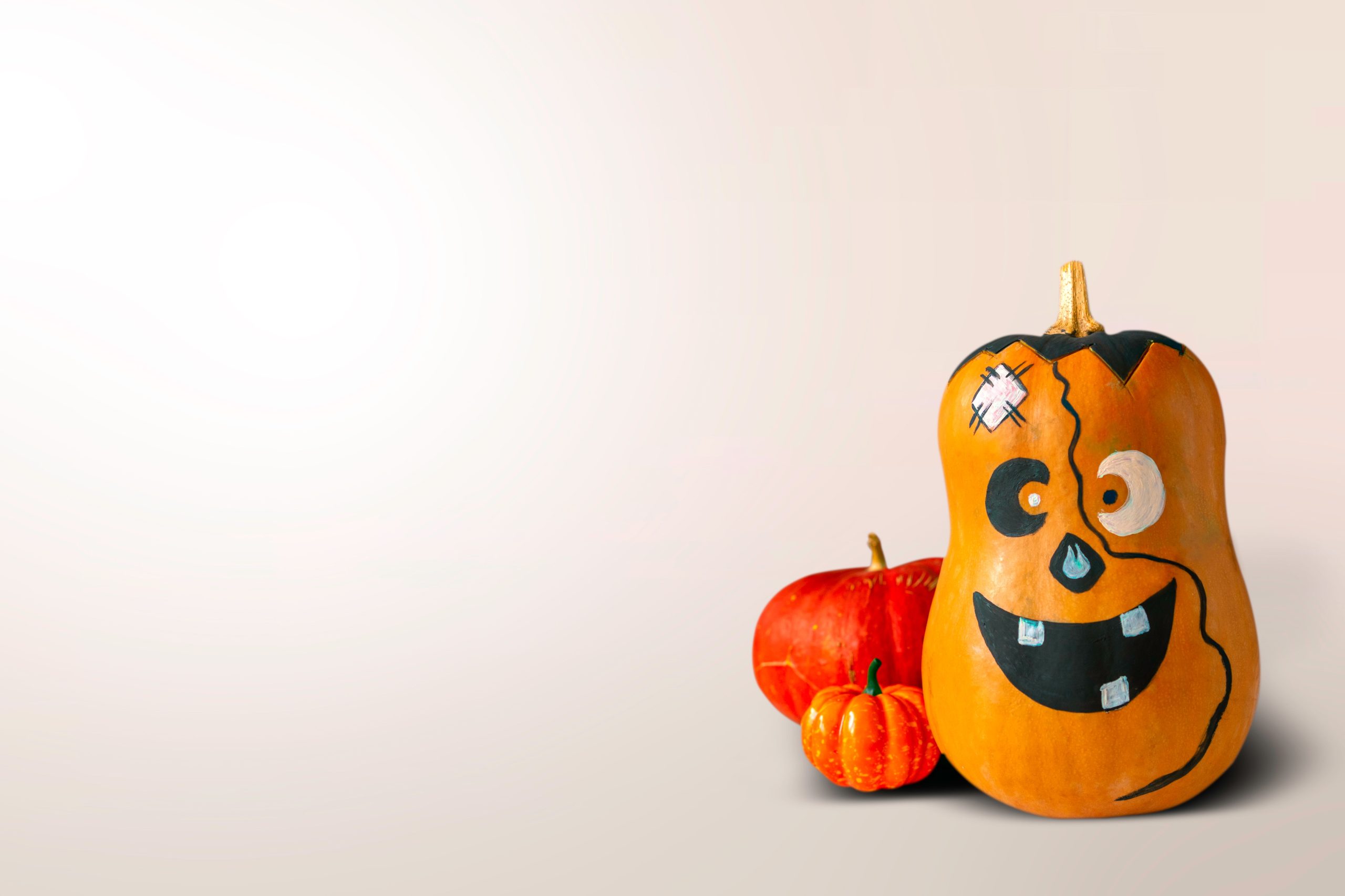 Three pumpkins with playful faces on a white background, ready for Halloween.