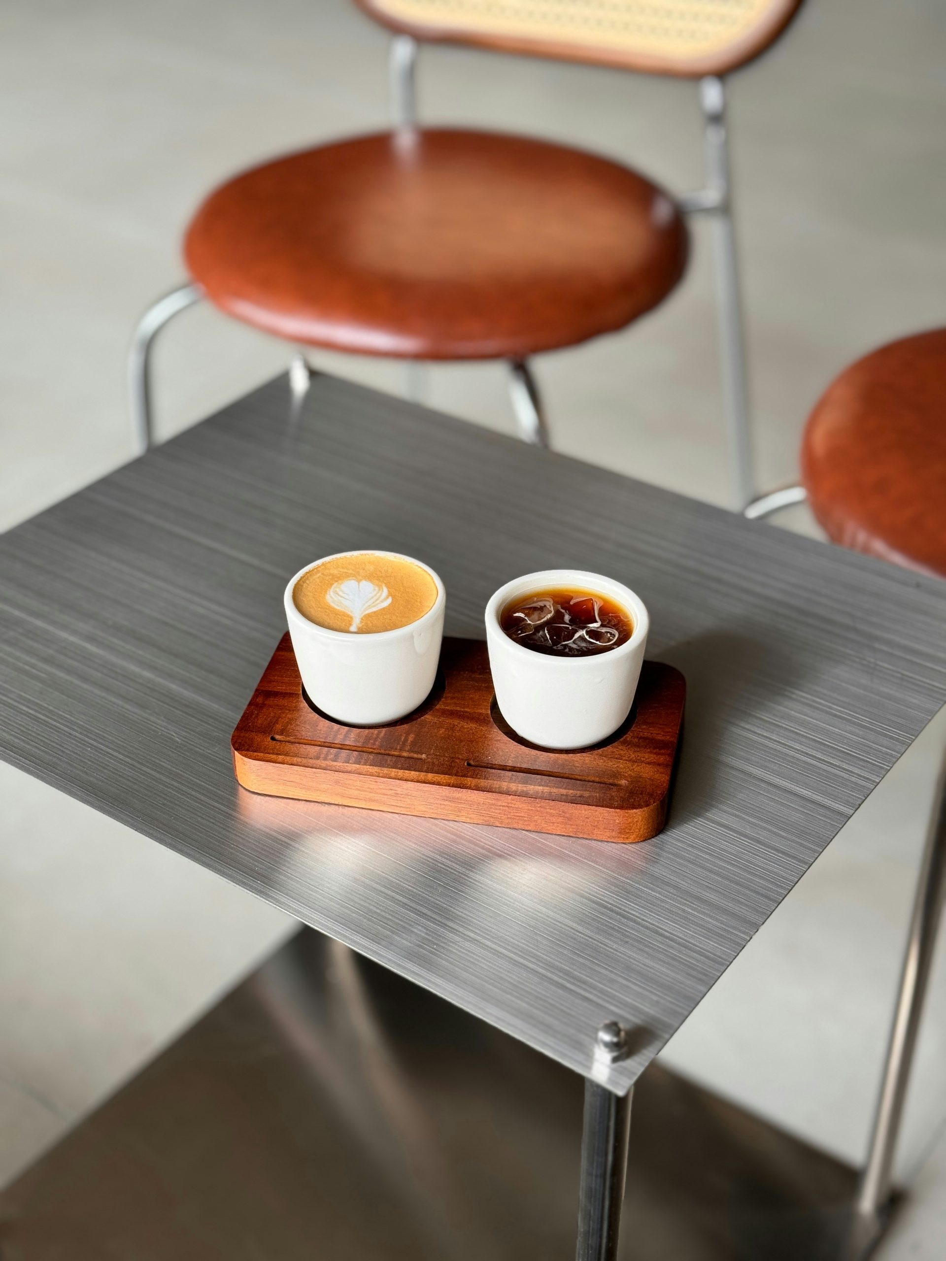 Two cups of coffee on a wooden tray.