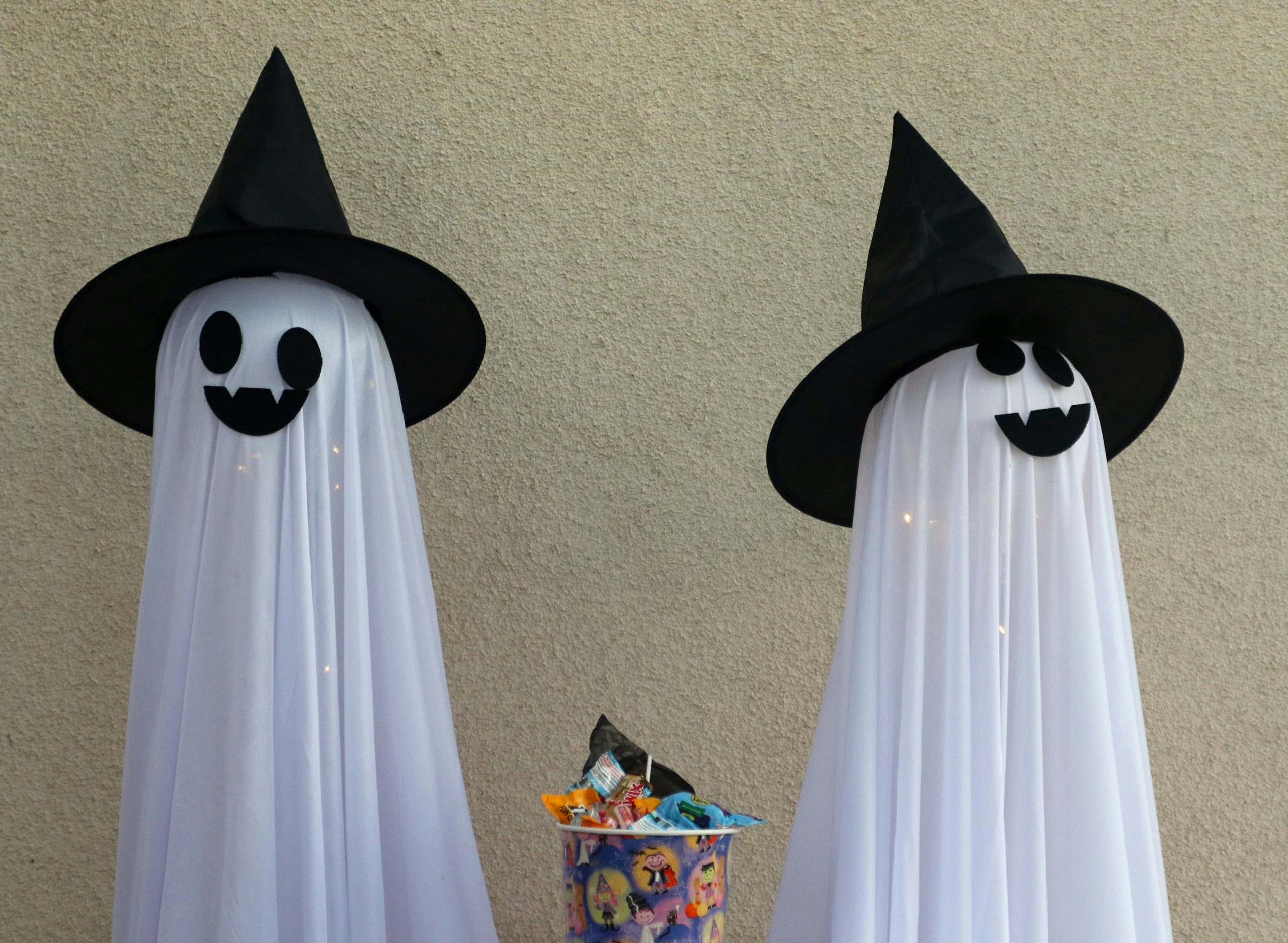 Two ghost decorations with witch hats and candy