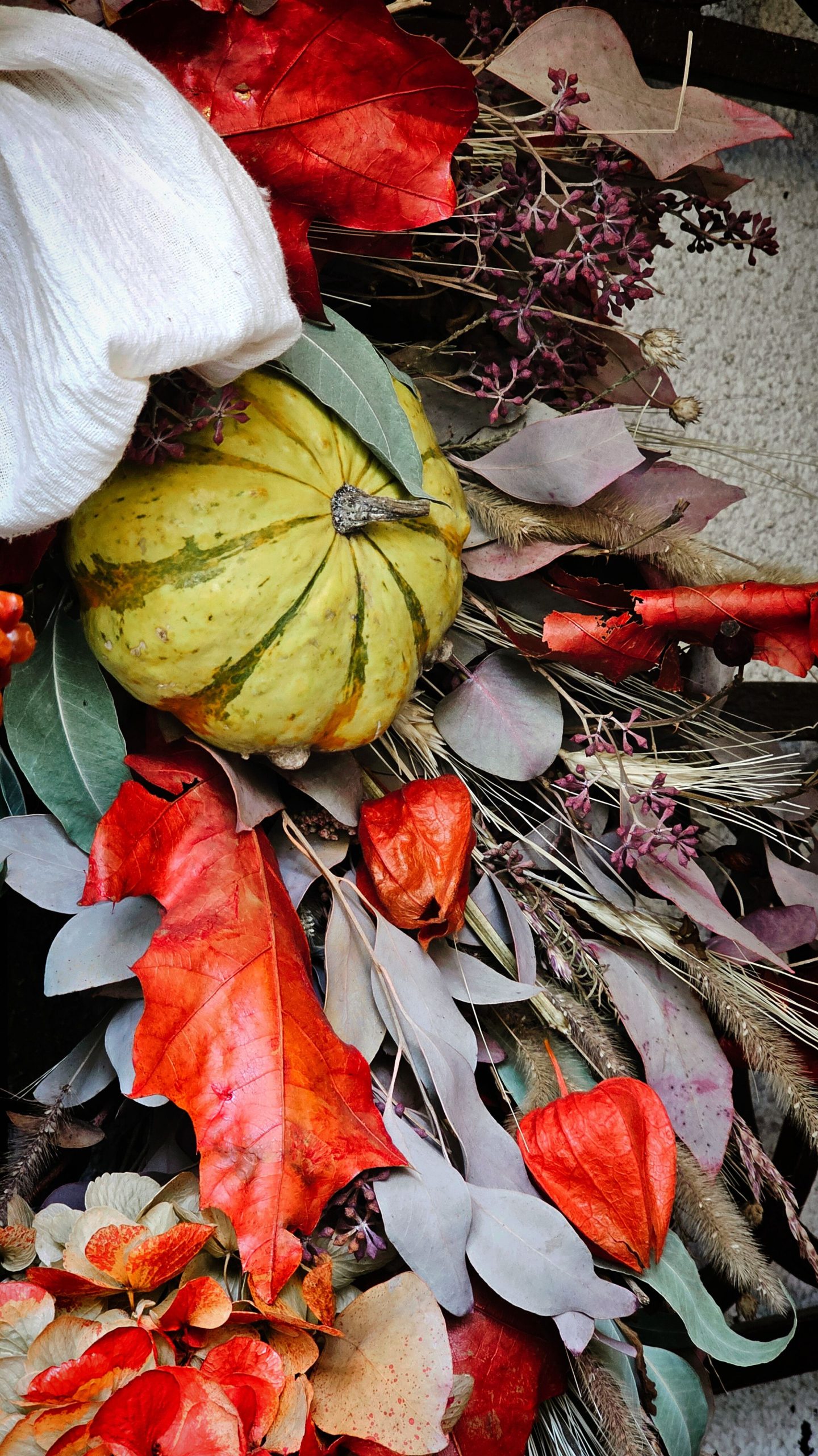 Vibrant autumn wreath featuring pumpkins, colorful leaves, and dried flowers, perfect for seasonal décor.