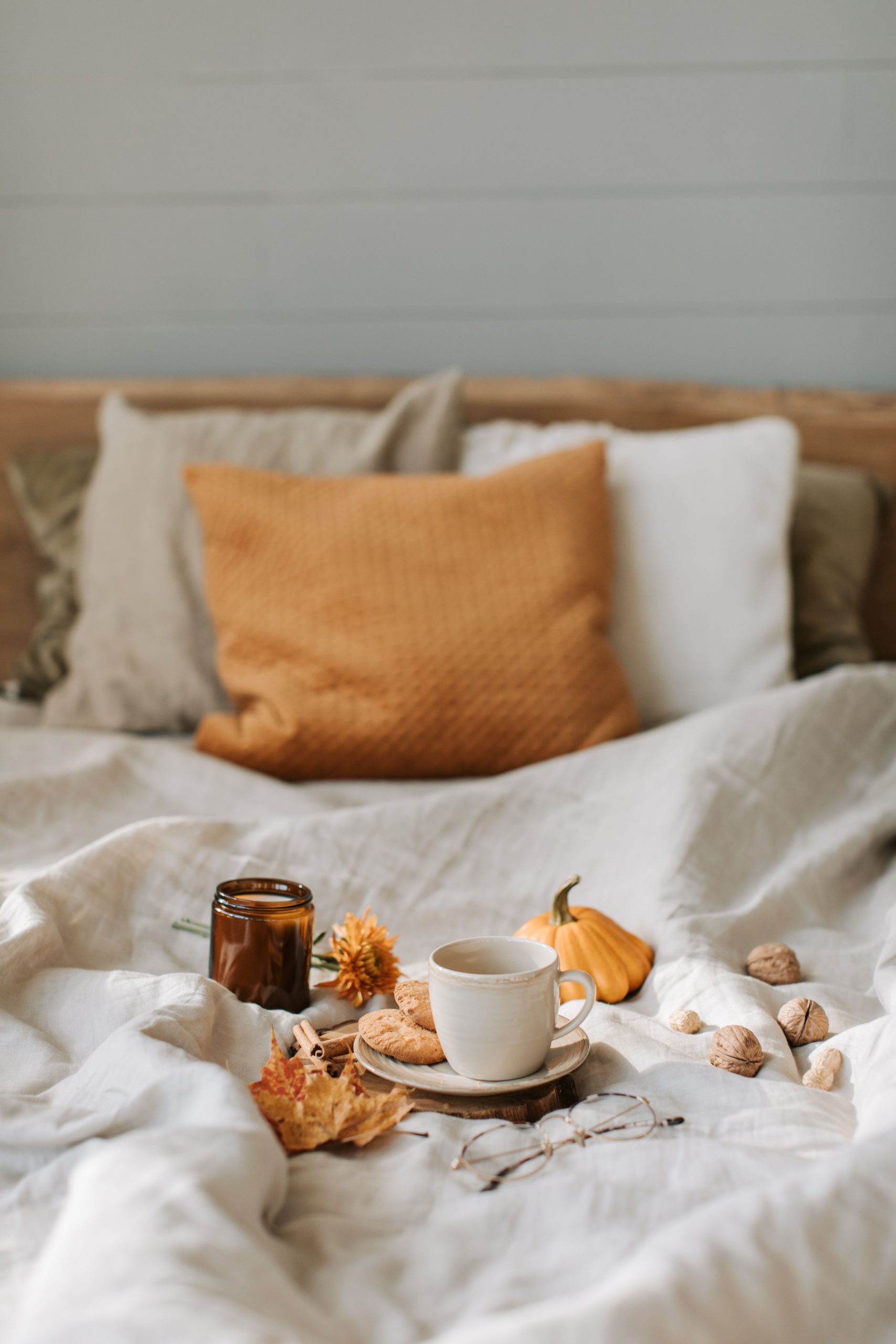 Warm and cozy bedroom scene with a tea cup, decorative autumn items, and soft textiles.