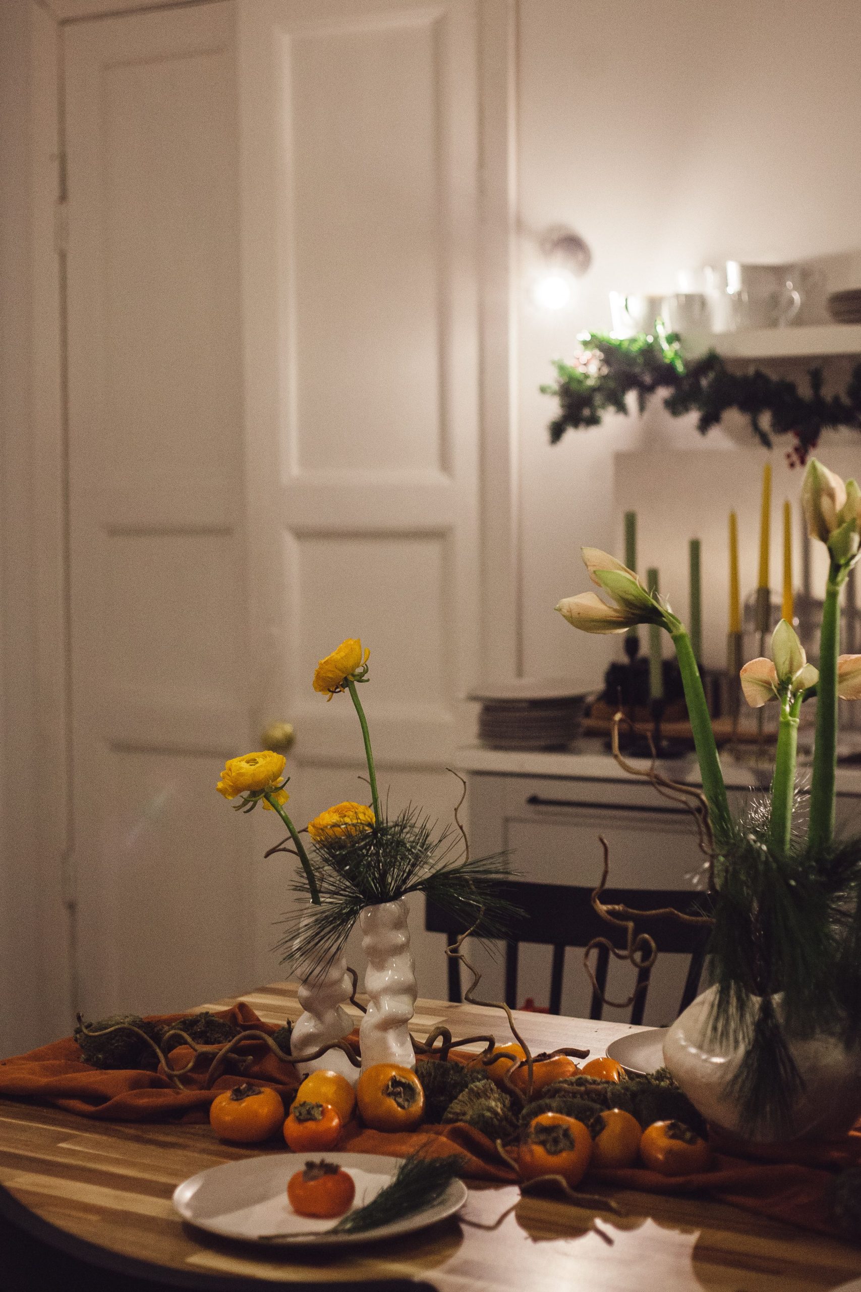 Warm and cozy dining room scene with floral arrangements and persimmons on the table, perfect for autumn vibes.