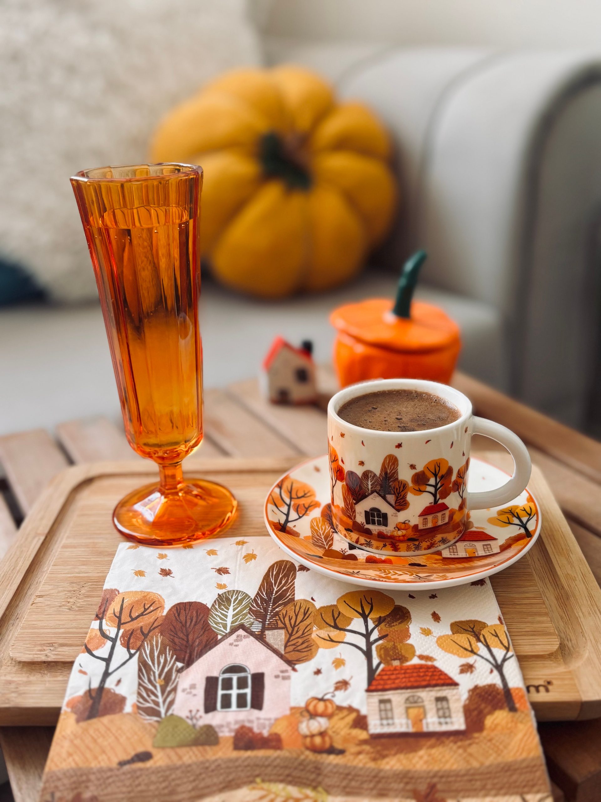 Warm autumn coffee setup with orange glass, pumpkin decor, and cozy vibes.
