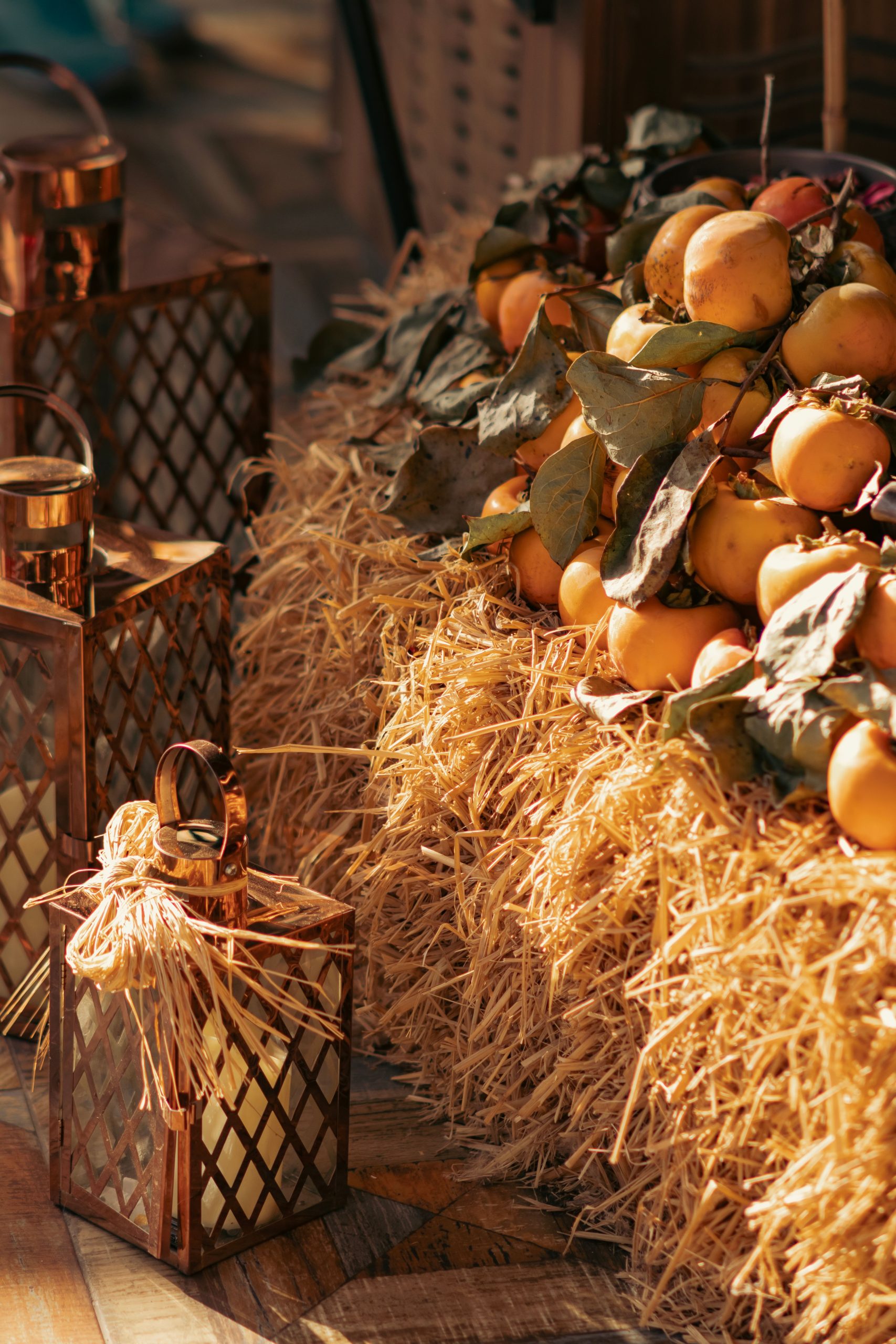 Warm autumn harvest scene featuring apples and lanterns on a straw bale, perfect for seasonal backgrounds.