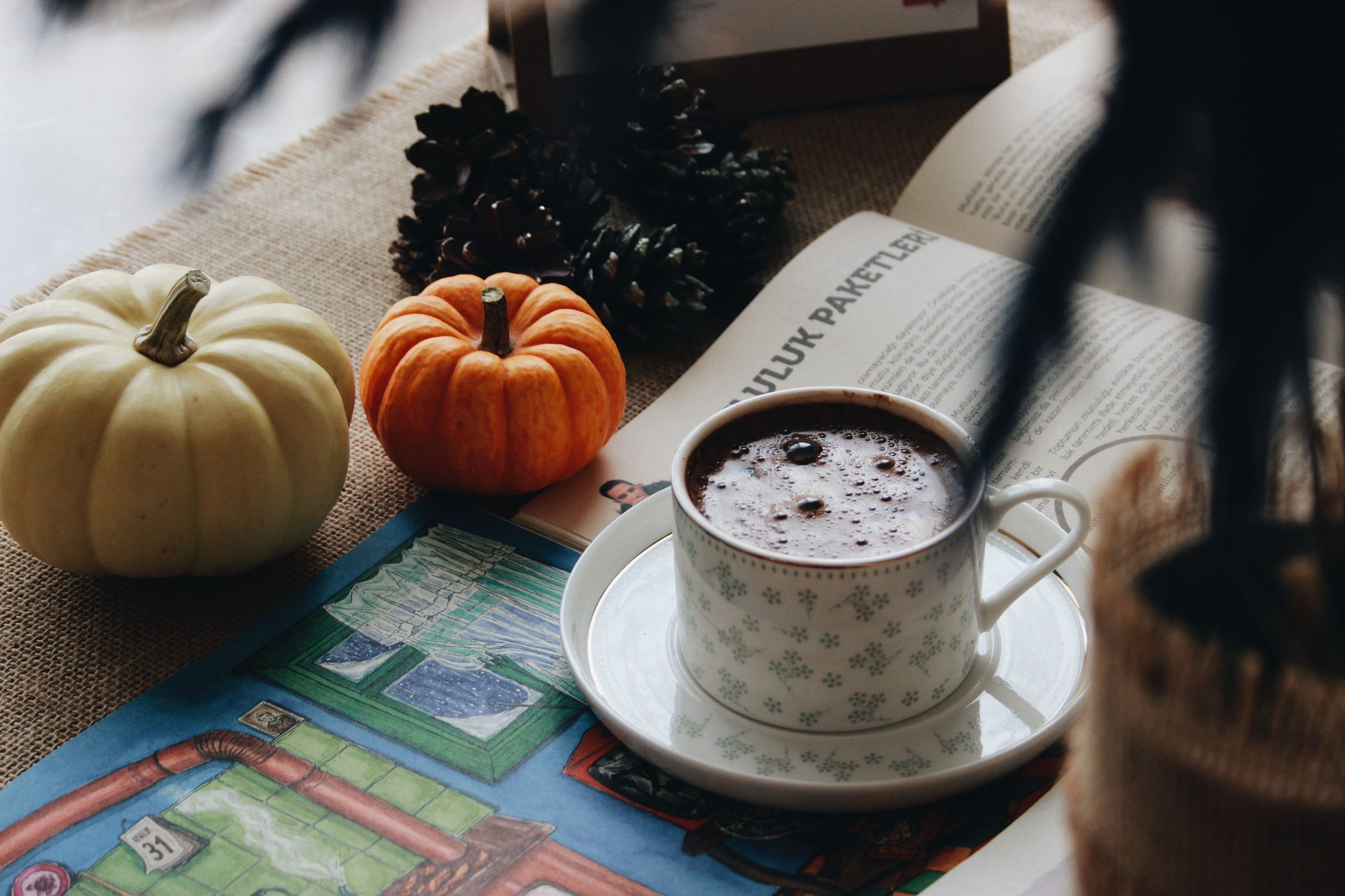 Warm autumn setup with a cup of coffee, pumpkins, and a magazine for a cozy vibe.
