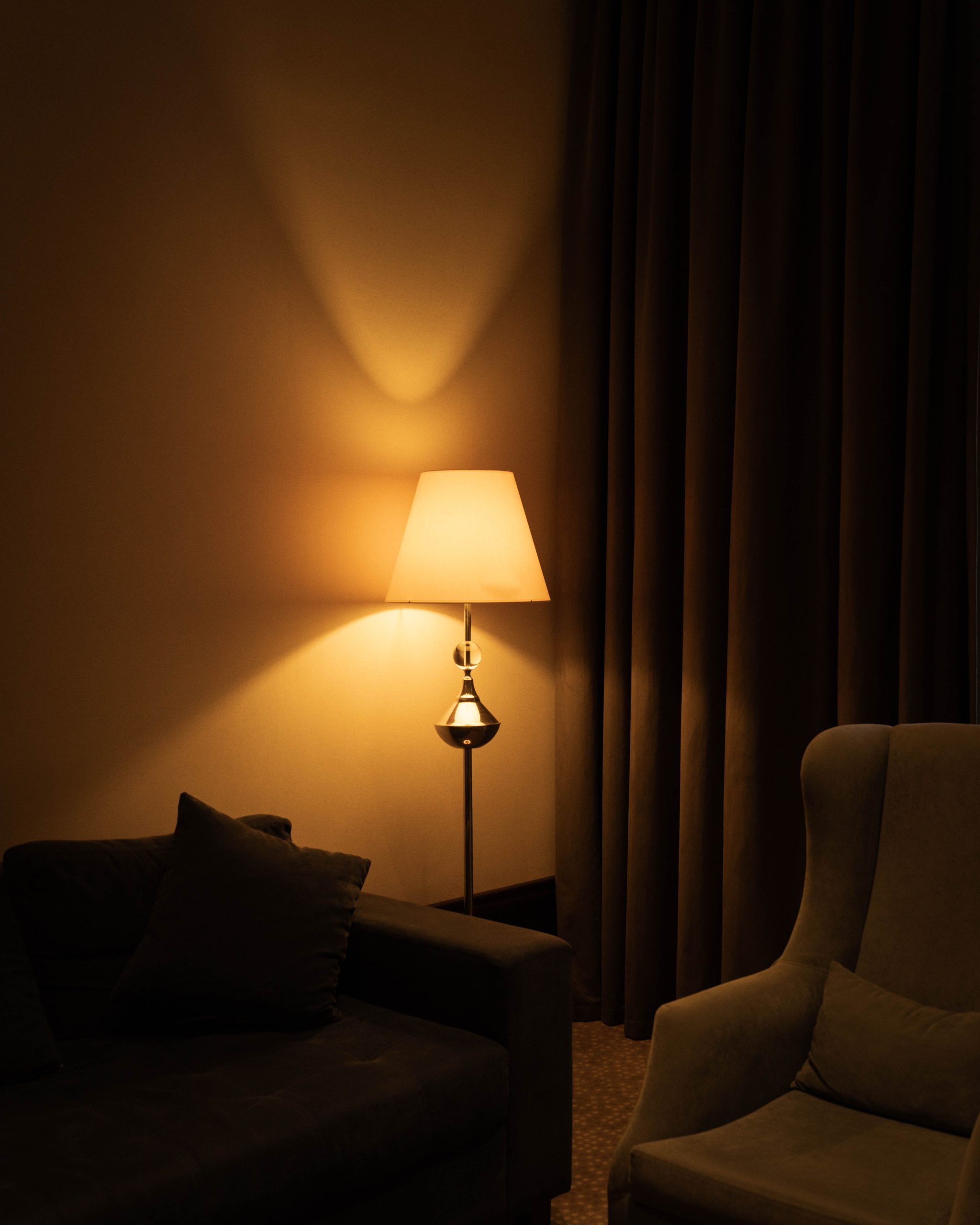 Warm, cozy living room corner with a lamp and sofa, perfect for relaxation.