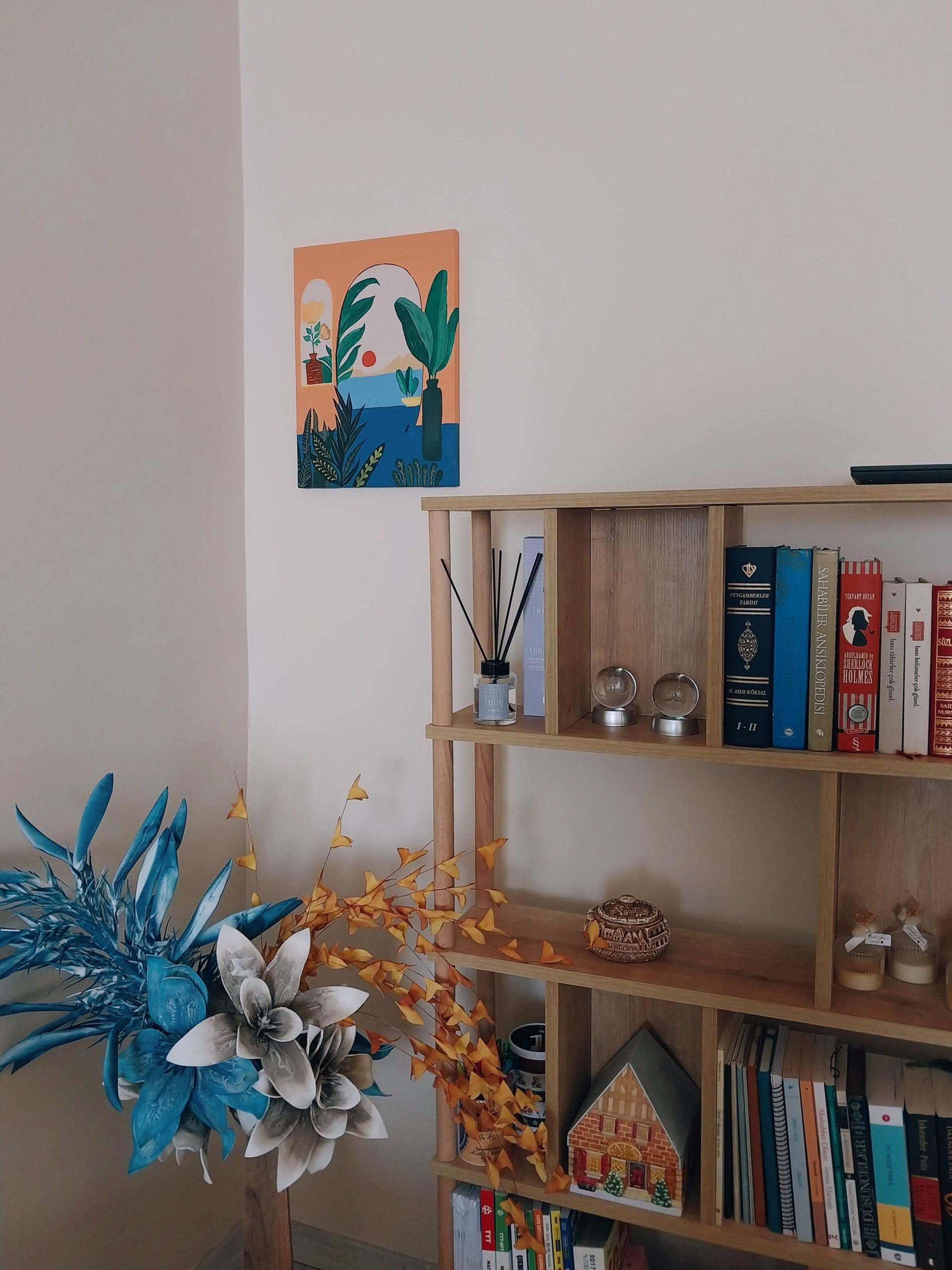 Warm indoor scene featuring a decorated bookshelf and wall art.