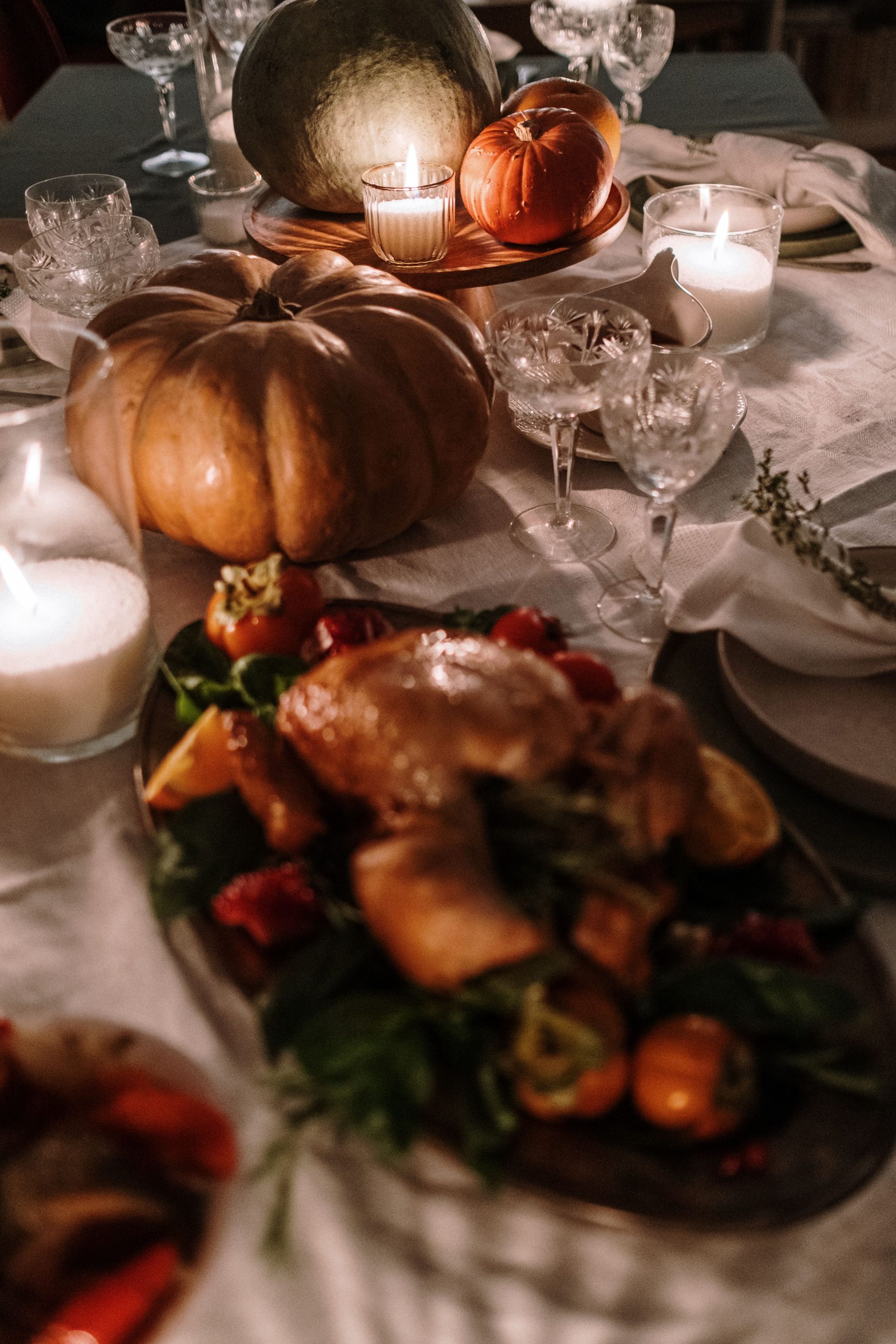 A beautifully arranged Thanksgiving dinner table with turkey, pumpkins, and candles creating a warm atmosphere.