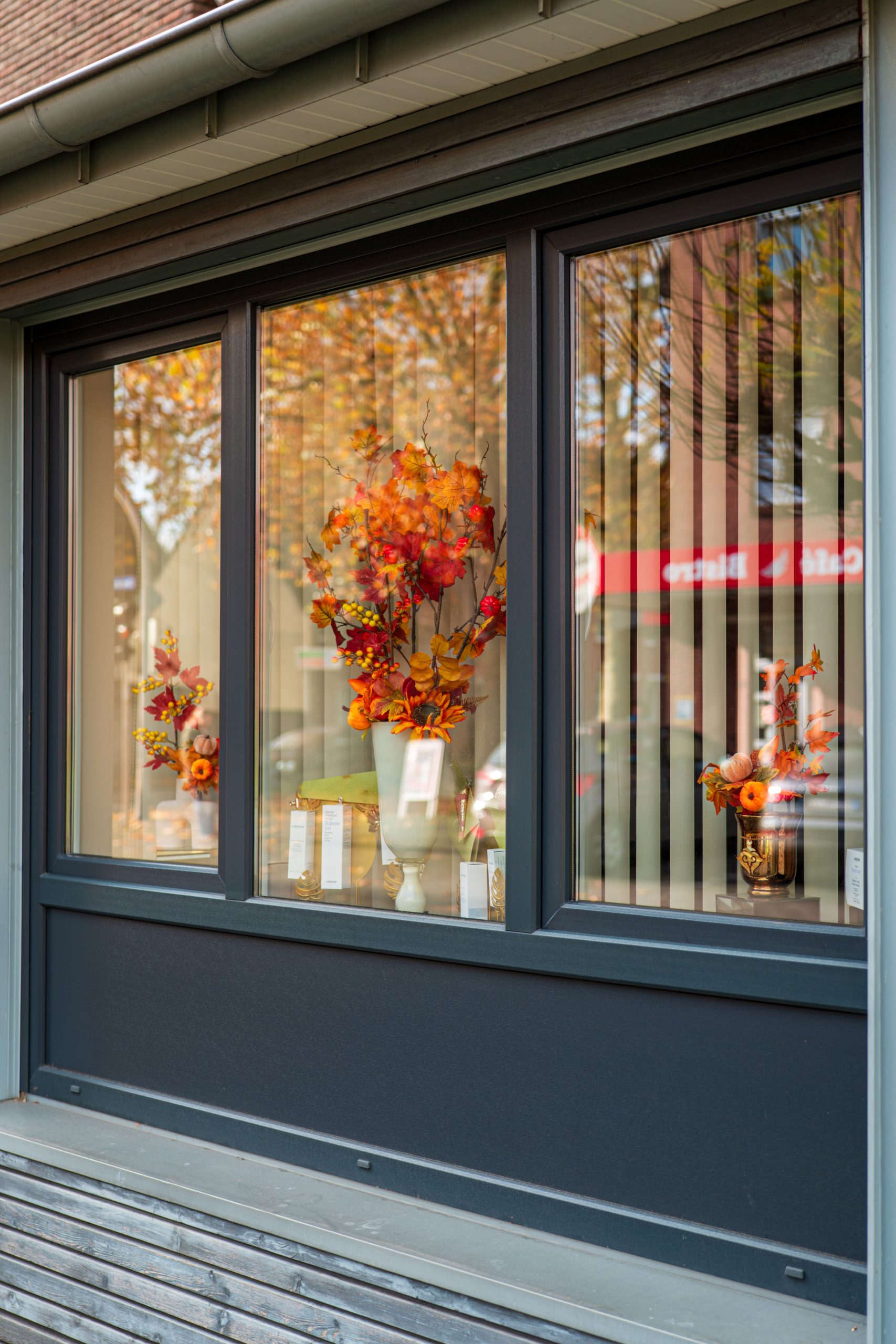 A charming floral arrangement with autumn colors displayed in a storefront window.