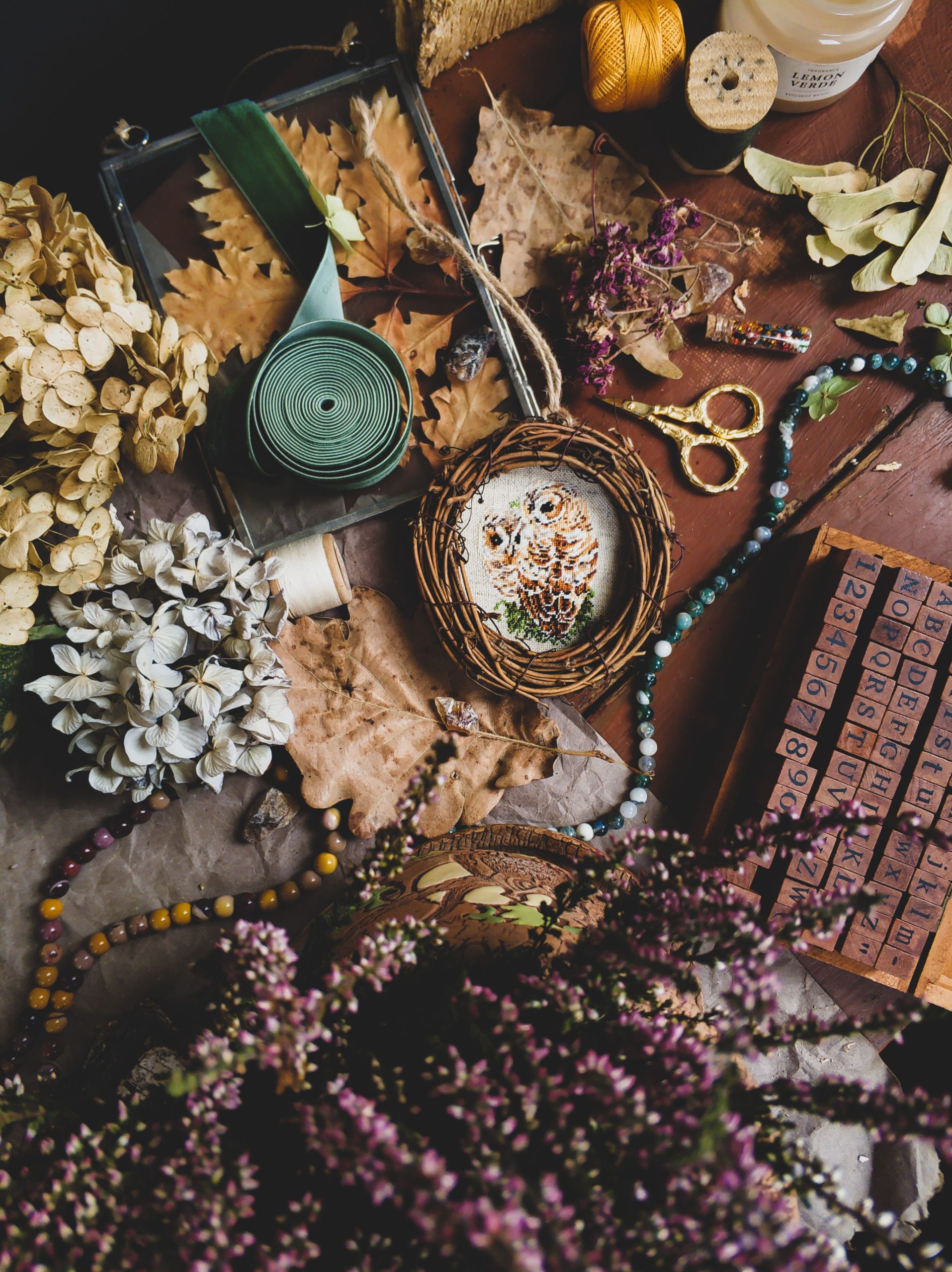 A cozy arrangement of crafting materials featuring dry flowers, ribbons, and sewing threads, perfect for fall inspiration.