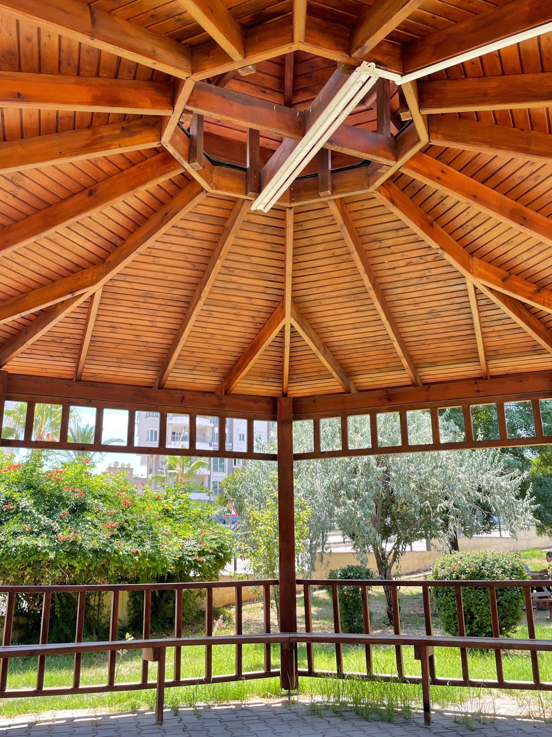 A detailed view of a wooden gazebo with lush greenery outside, perfect for relaxation.