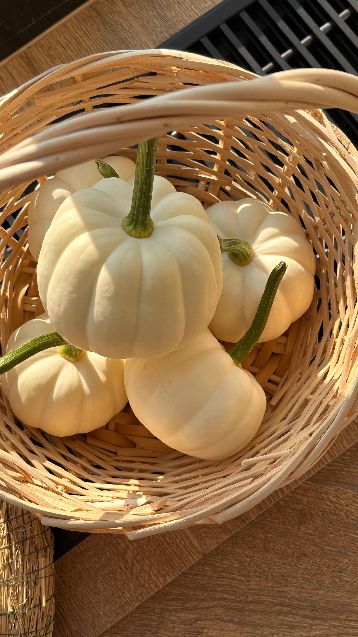 A wicker basket filled with small white pumpkins, perfect for autumn and Halloween decorations.