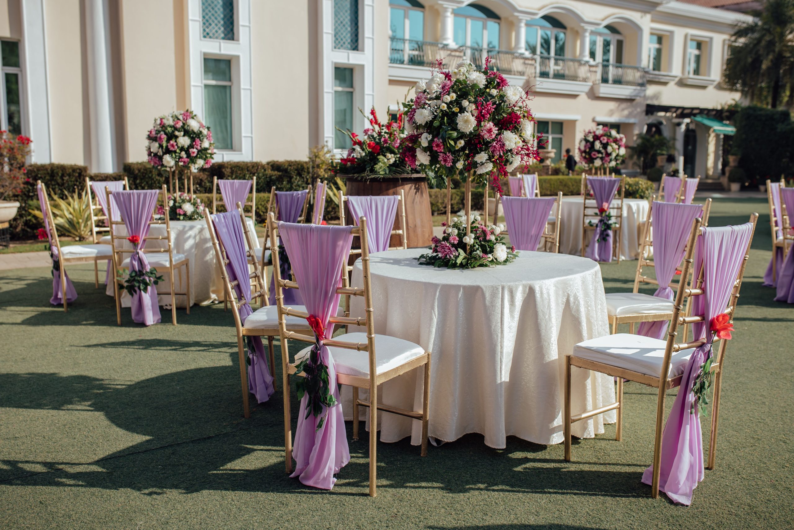 Beautiful outdoor wedding reception area with floral arrangements and lavender chairs.