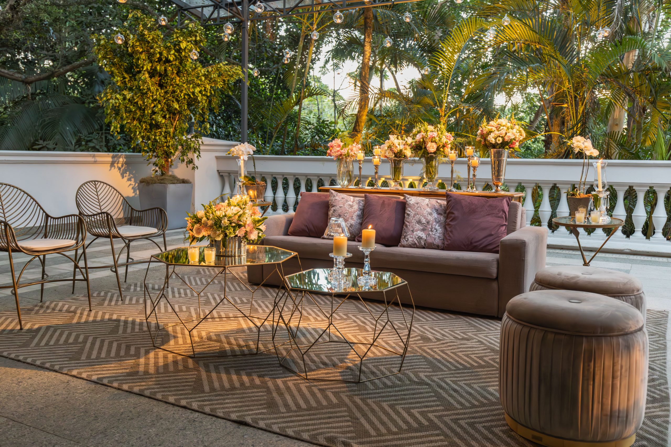 Beautifully decorated outdoor lounge area with sofa, glass tables, and plants.