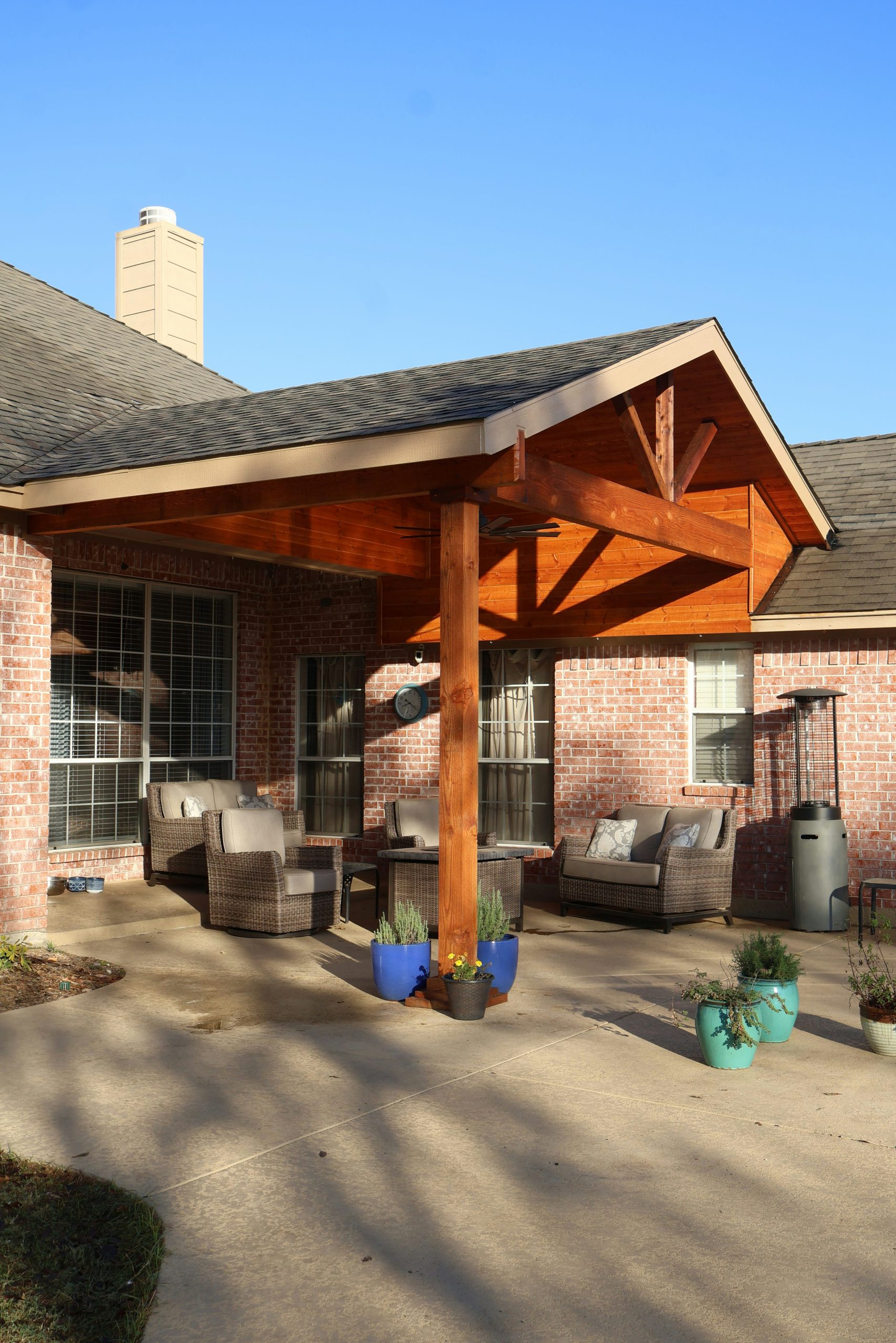 Brick house with wooden covered patio and outdoor furniture