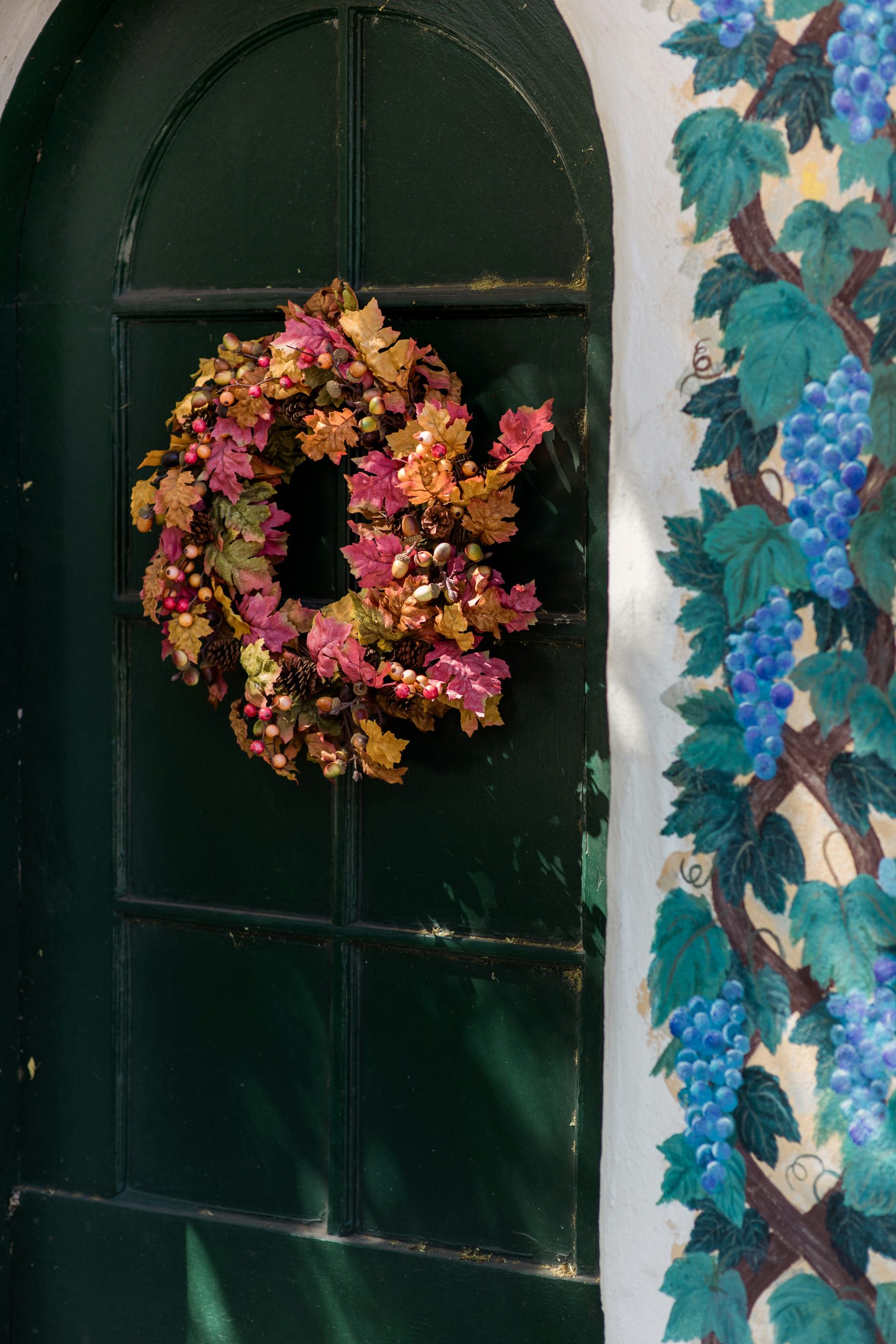 brown and red maple wreath on green arch door