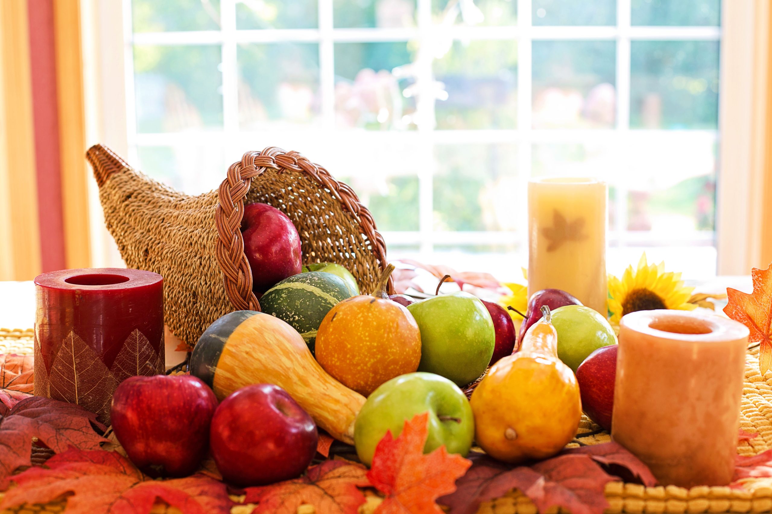 Colorful cornucopia with fruits and candles celebrating the fall harvest season.