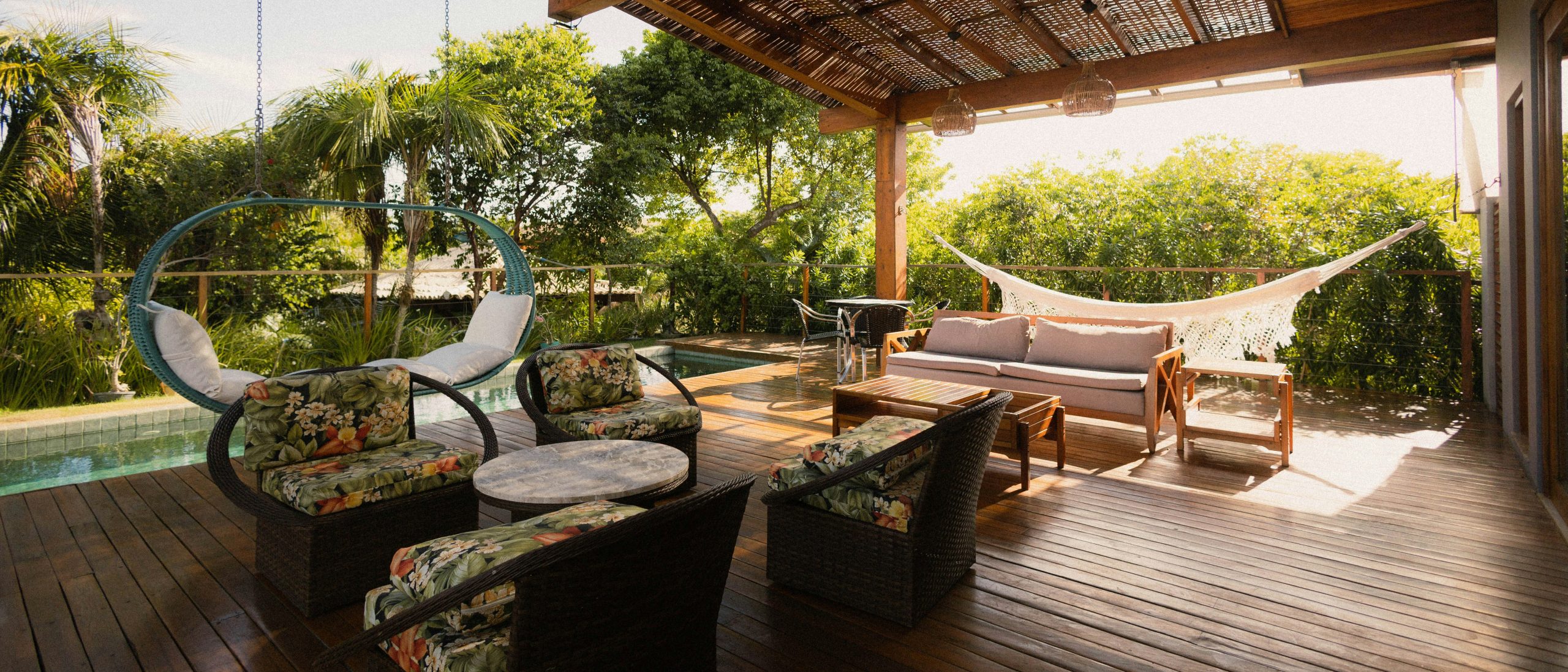 Covered patio with seating, hammock, and pool view