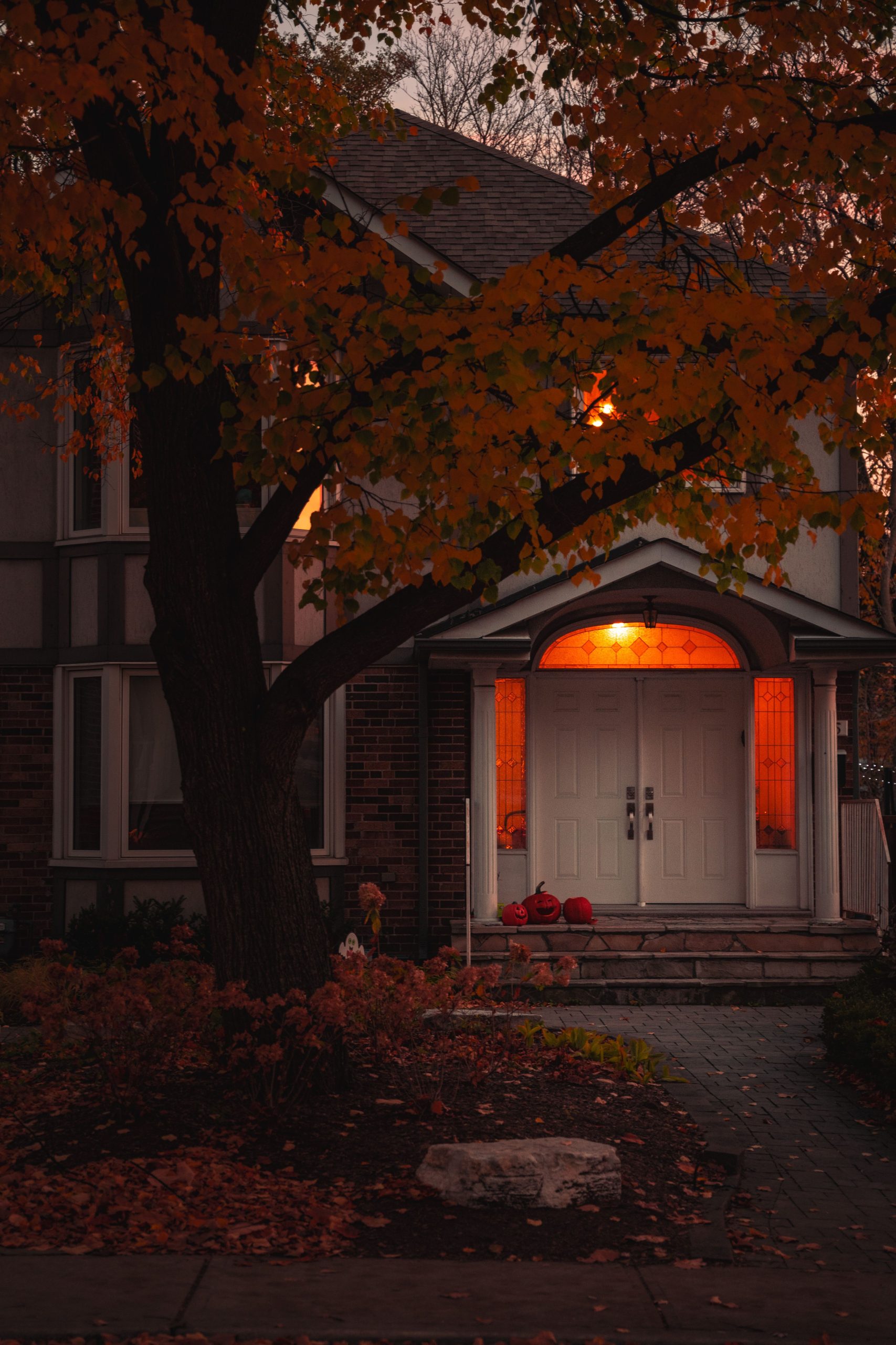 Cozy fall evening view of a house entry surrounded by colorful autumn leaves.