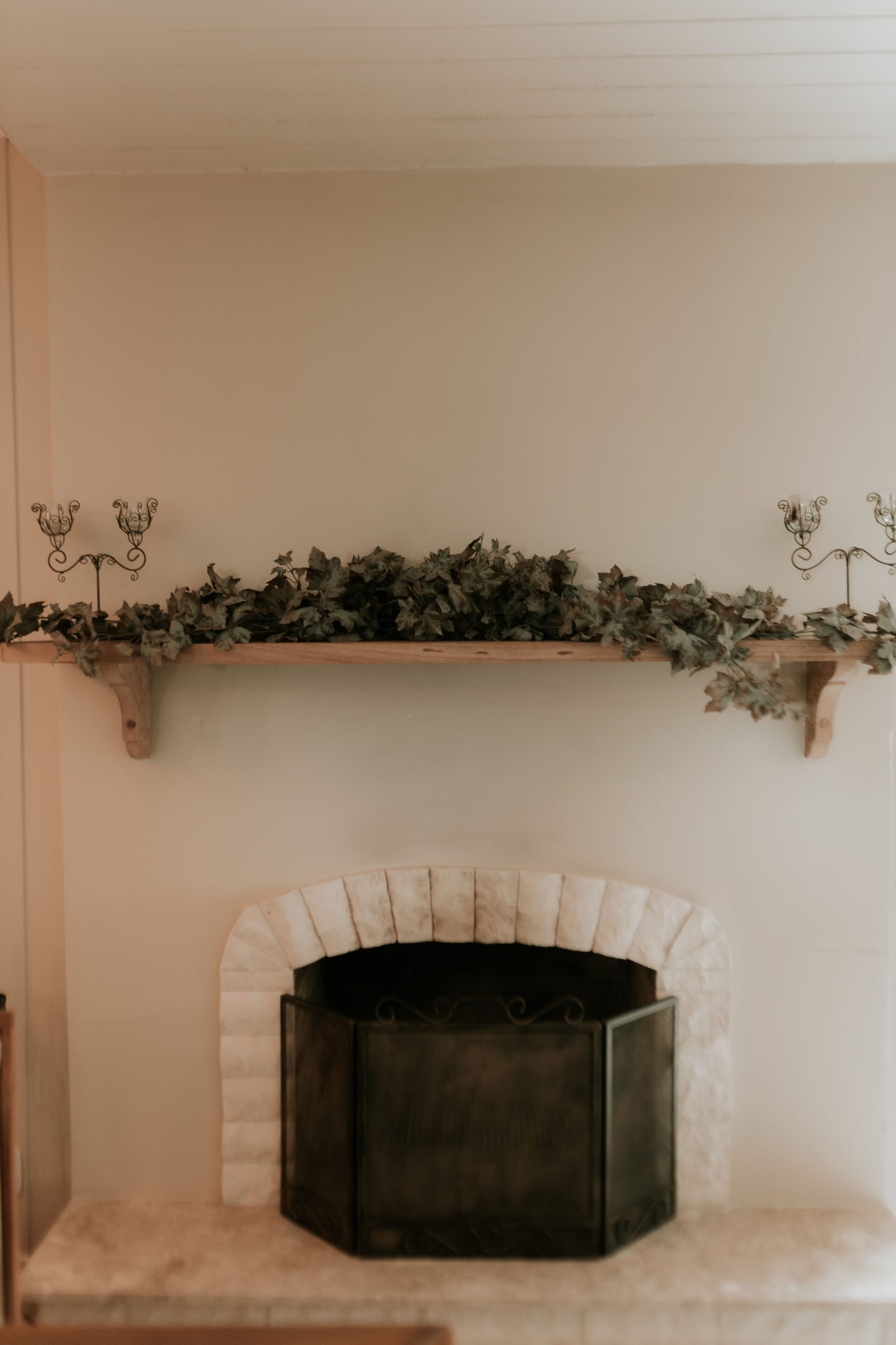 Elegant fireplace with greenery and ornate candleholders creates a warm, inviting ambiance.
