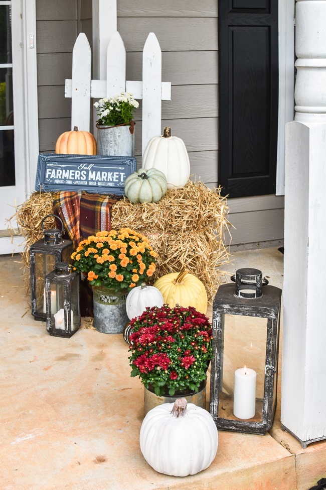 Farmhouse front porch filled with lots of pumpkins, mums, and haybales