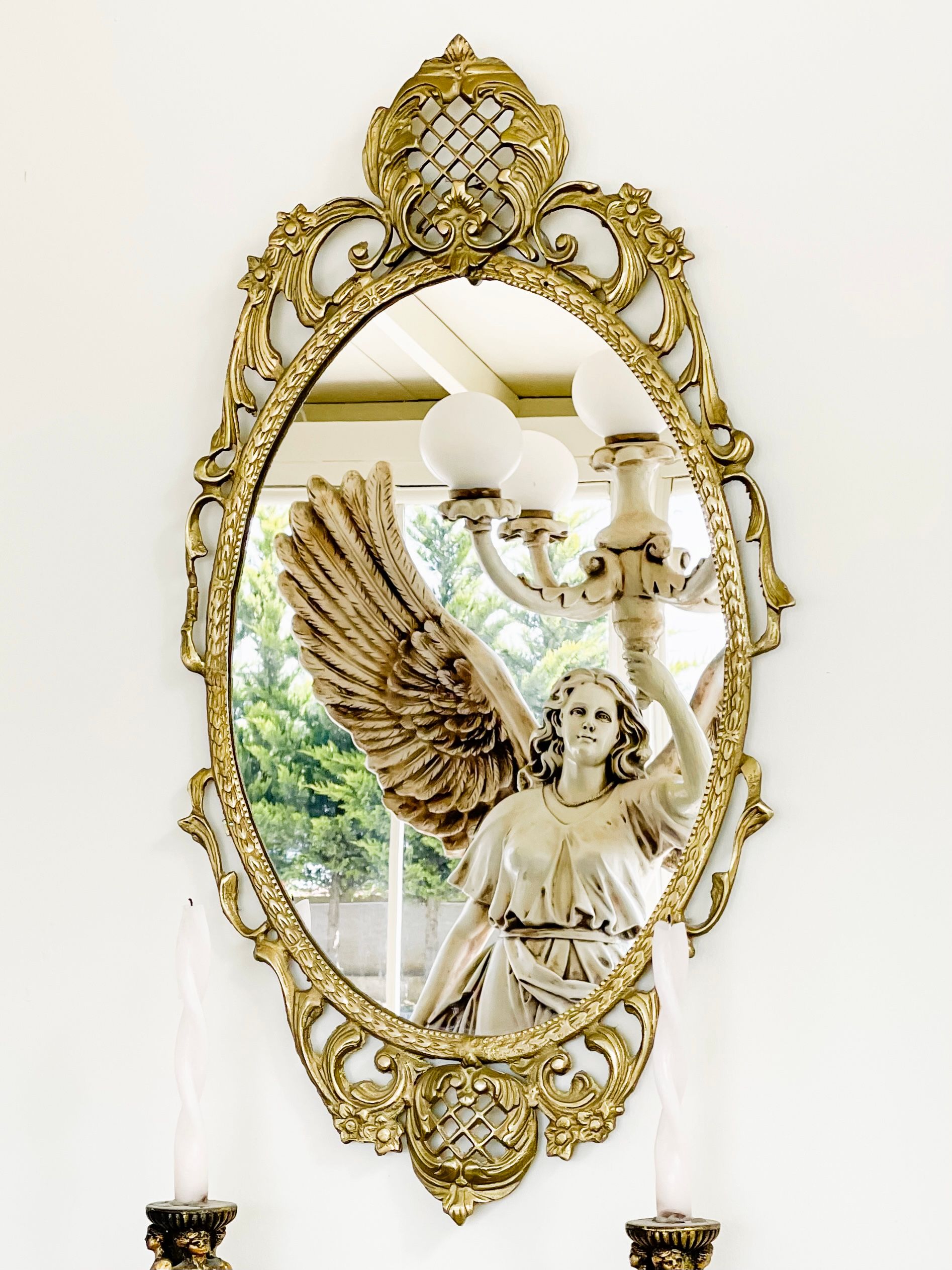 Intricately designed gold mirror reflecting winged angel statue, adding a touch of elegance.