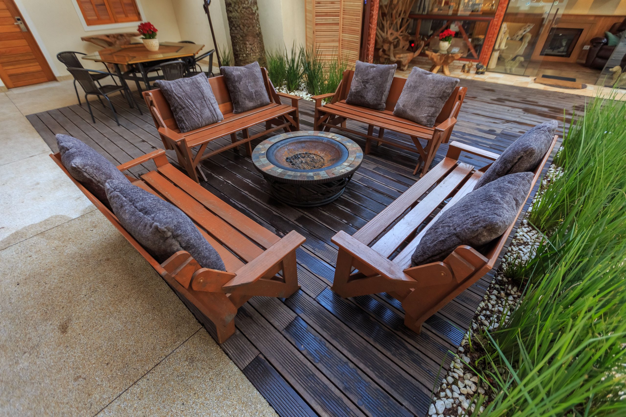 Inviting outdoor lounge with wooden benches and central fire pit, perfect for gatherings.