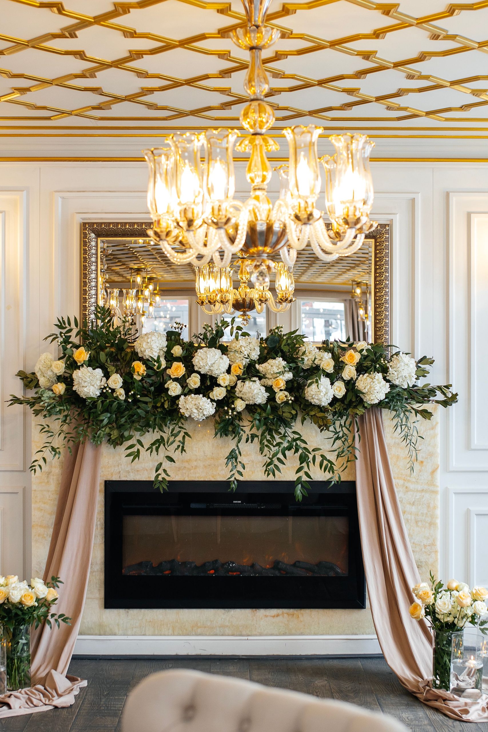 Luxurious interior with chandelier and floral decor over fireplace. Perfect for high-end design concepts.