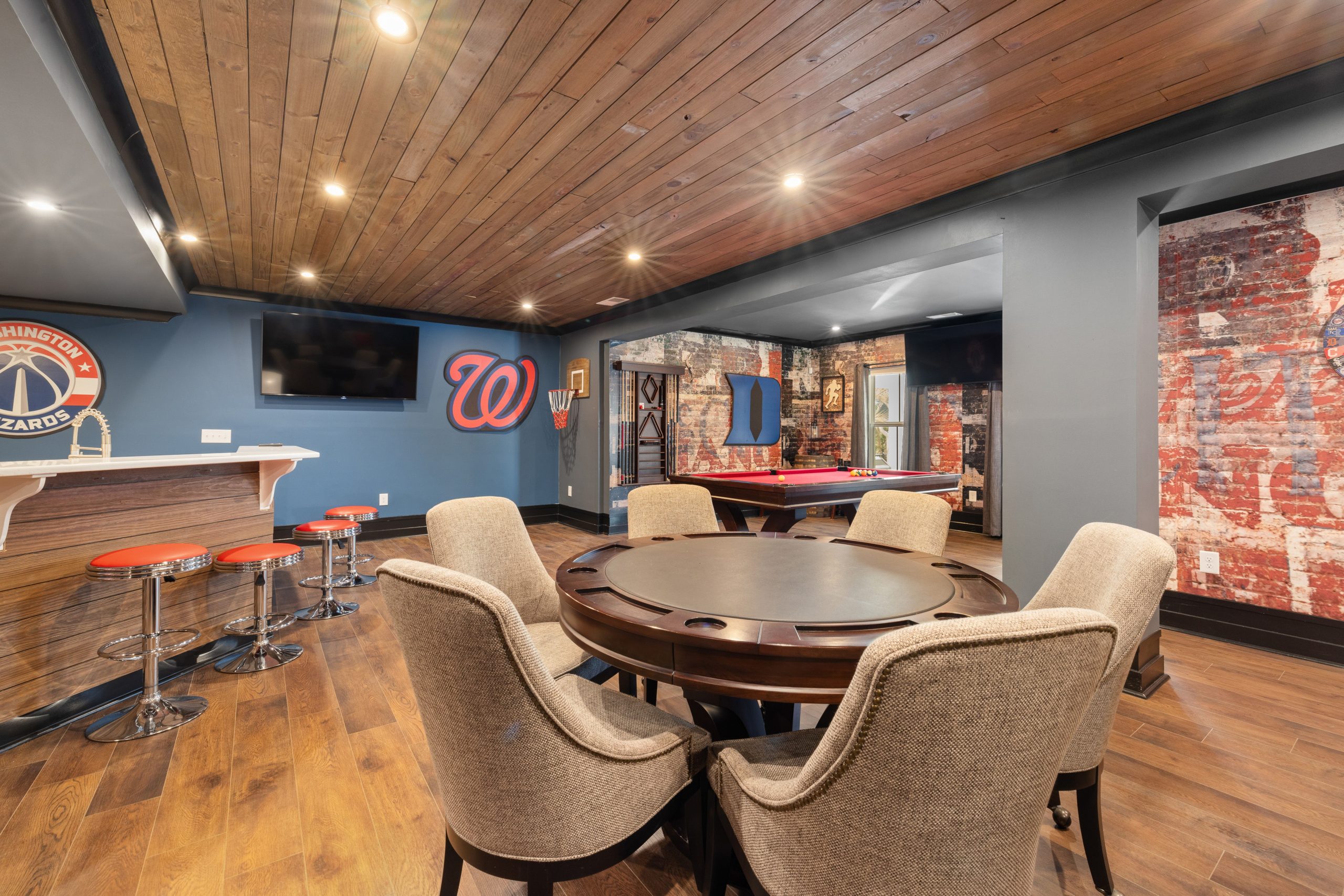 Modern basement game room with bar, seating, and pool table.