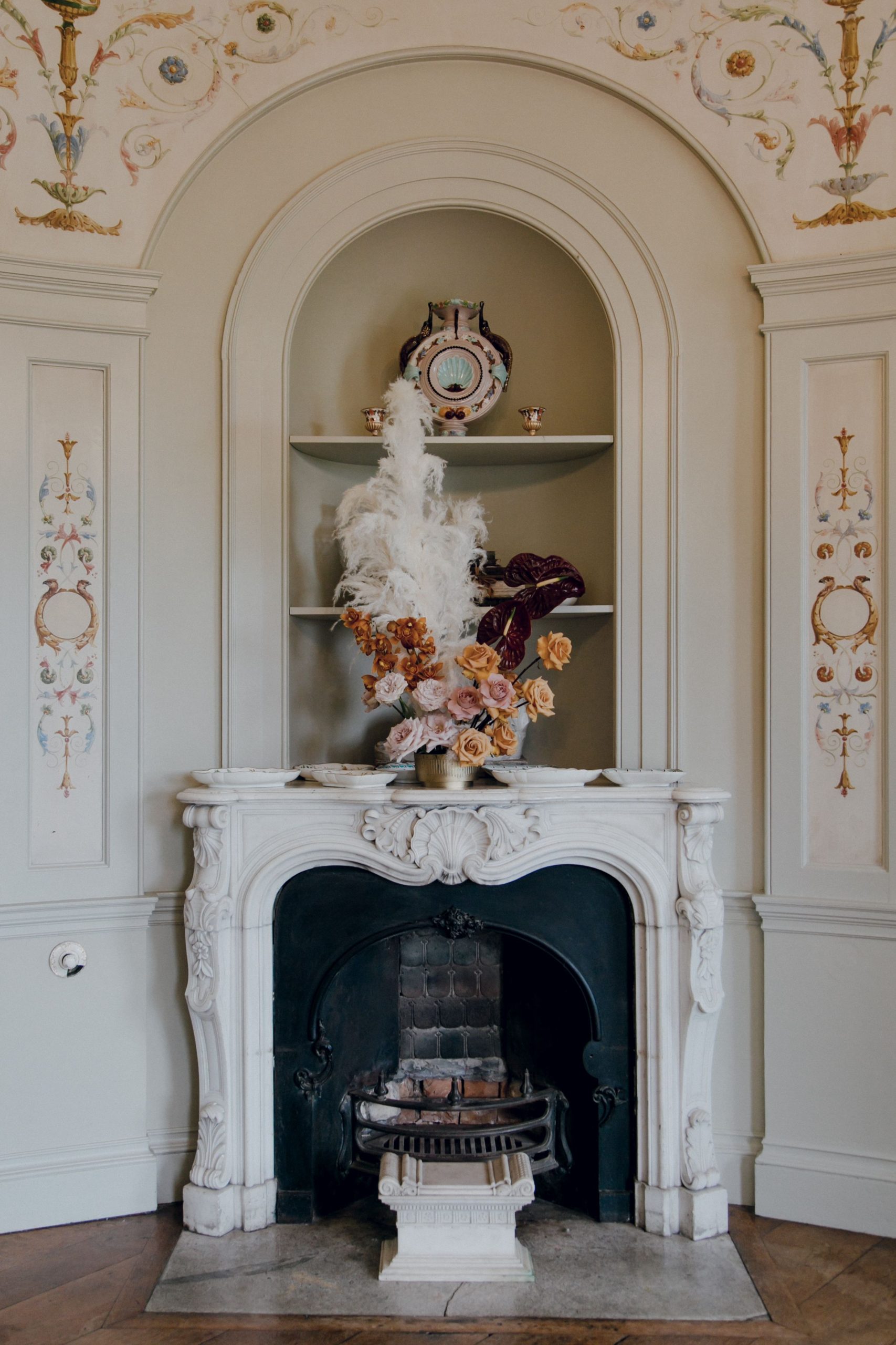 Ornate interior design with a classic fireplace and floral arrangement, ideal for elegant settings.