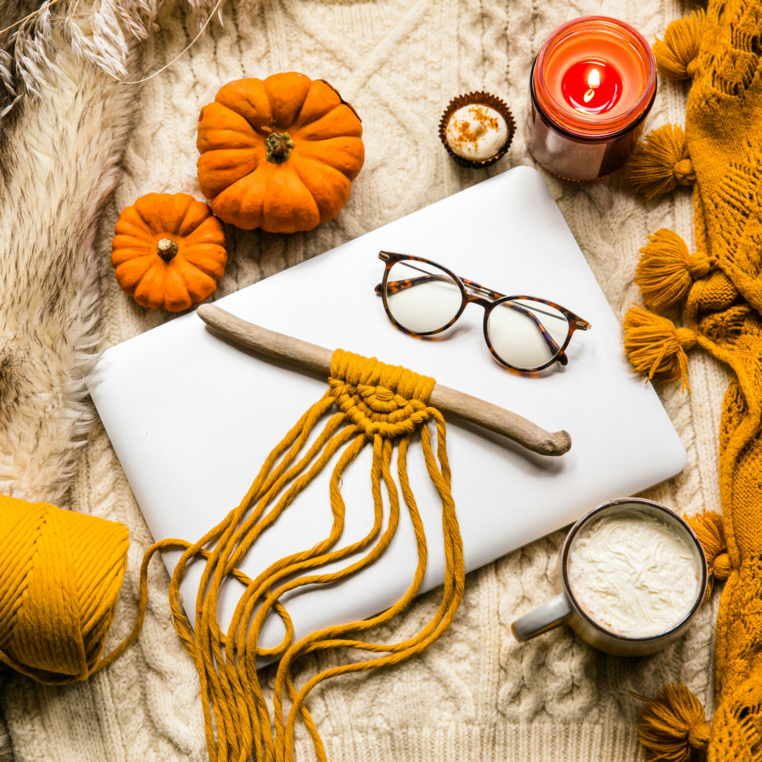 Out of office for the holidays! Closed laptop with natural macrame, glasses, candles, string, pumpkins, cake and rugs. Part of the Fireside in Autumn Collection.