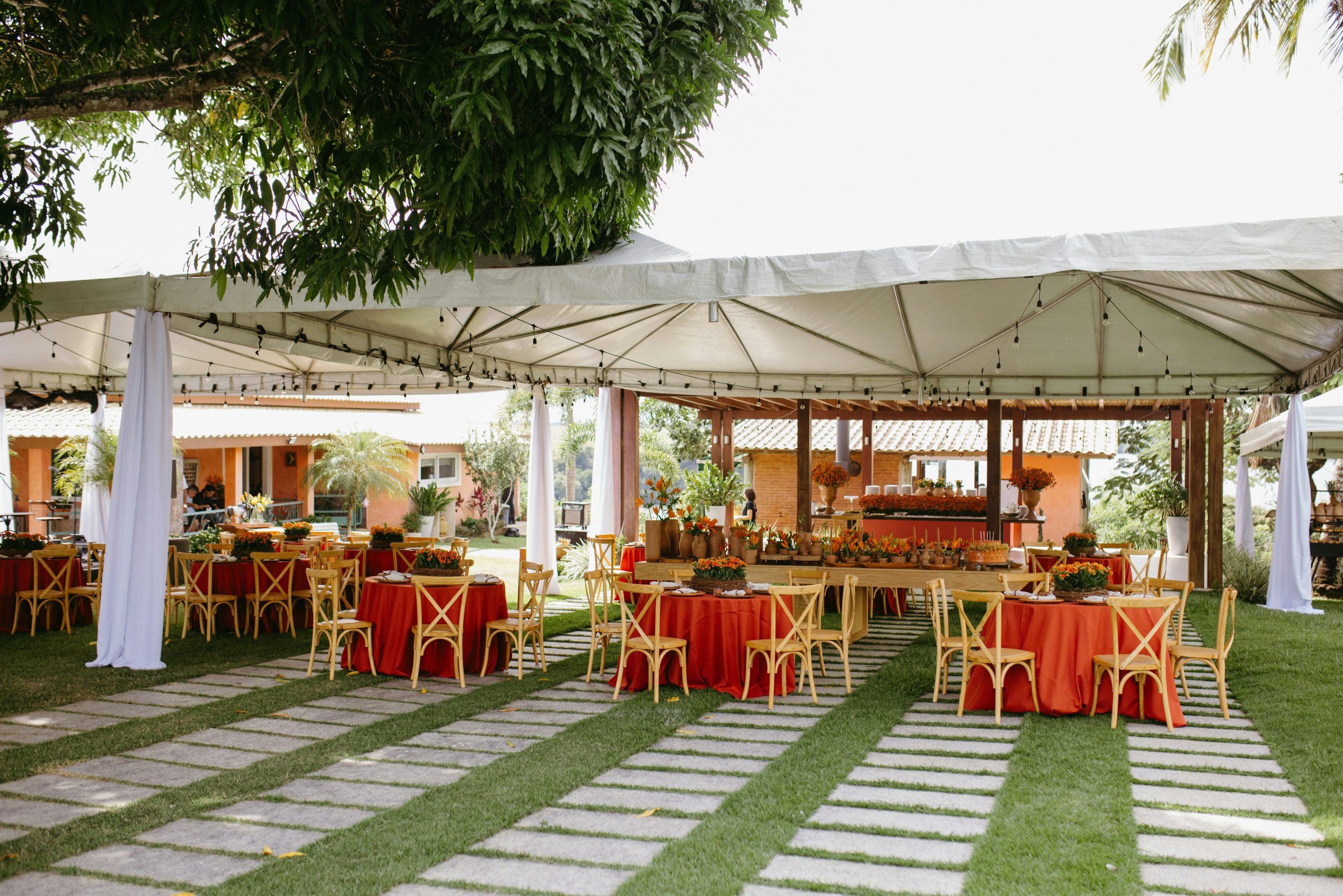 Outdoor event setup with tables, chairs, and tents on grass