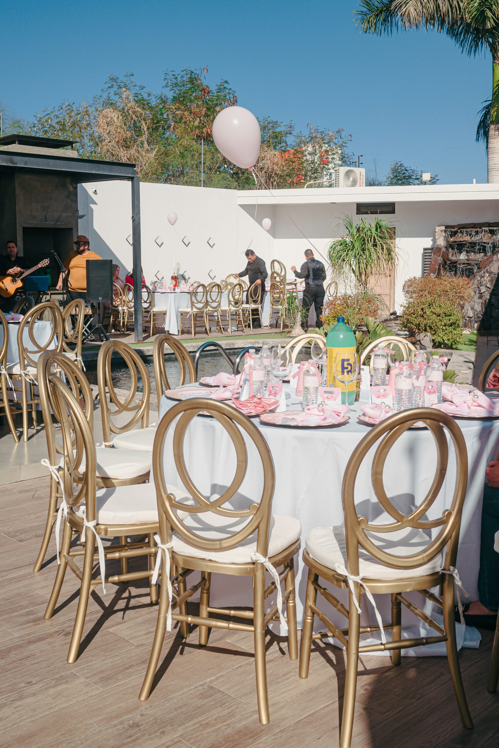 Outdoor tables set for a party with gold chairs