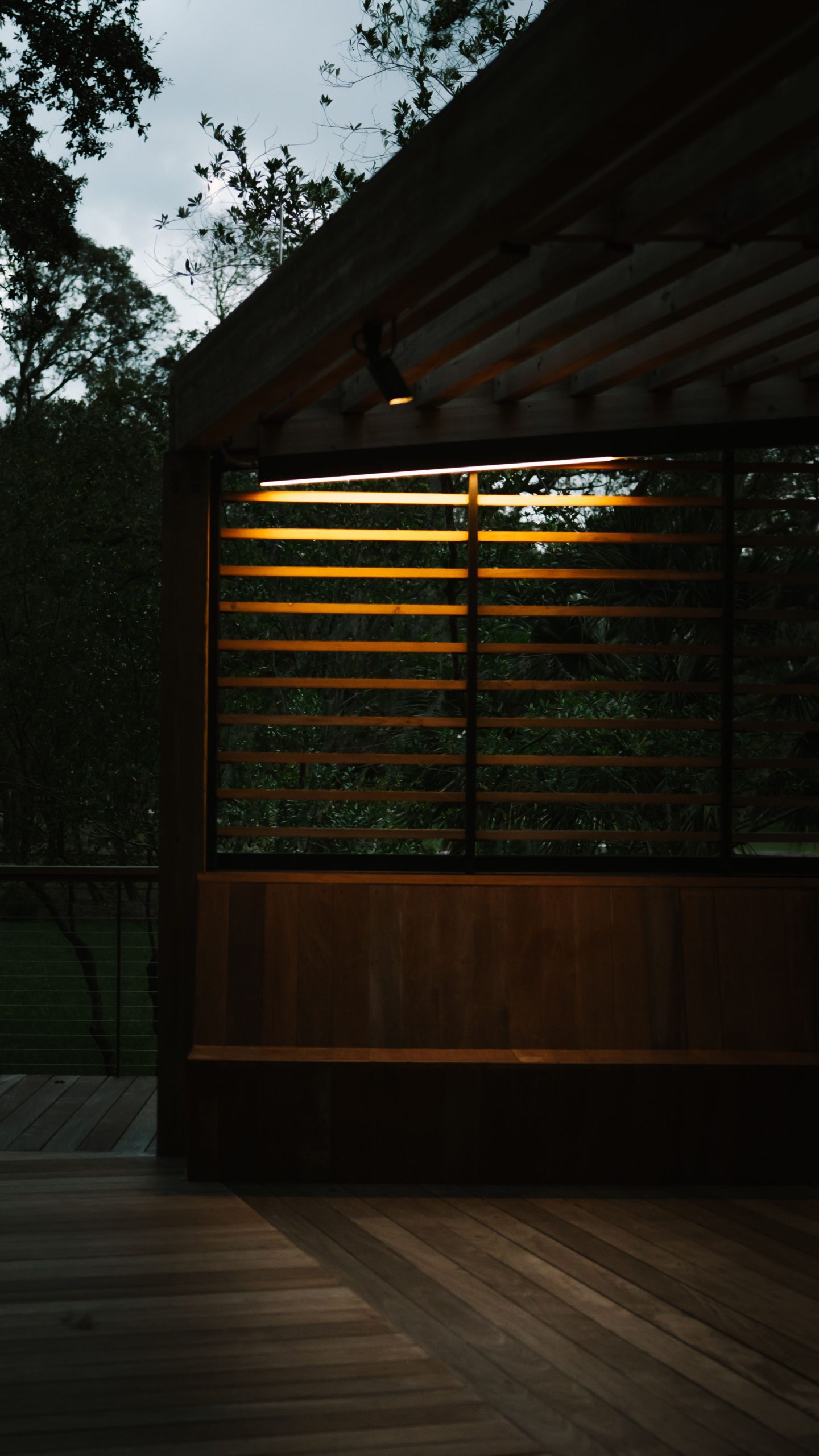 Outdoor wooden patio with warm evening lighting and wooden bench.