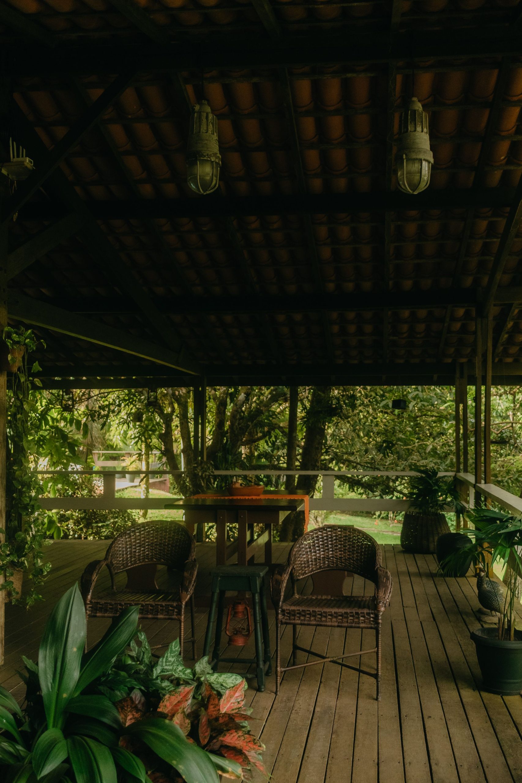 Peaceful outdoor patio with wicker chairs and lush greenery.